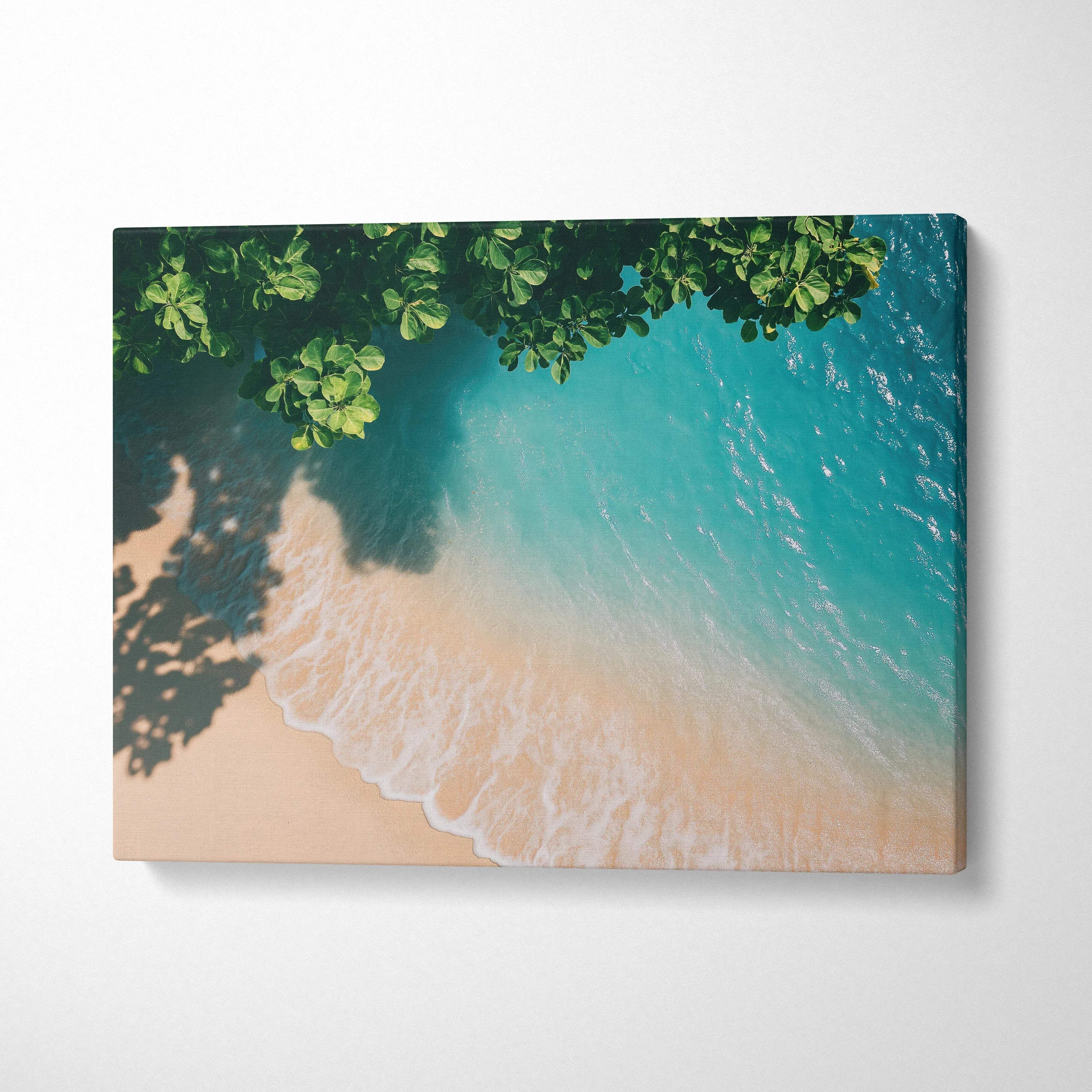 Canvas wall art featuring tranquil beach with turquoise ocean waves and overhead green foliage shadow.
