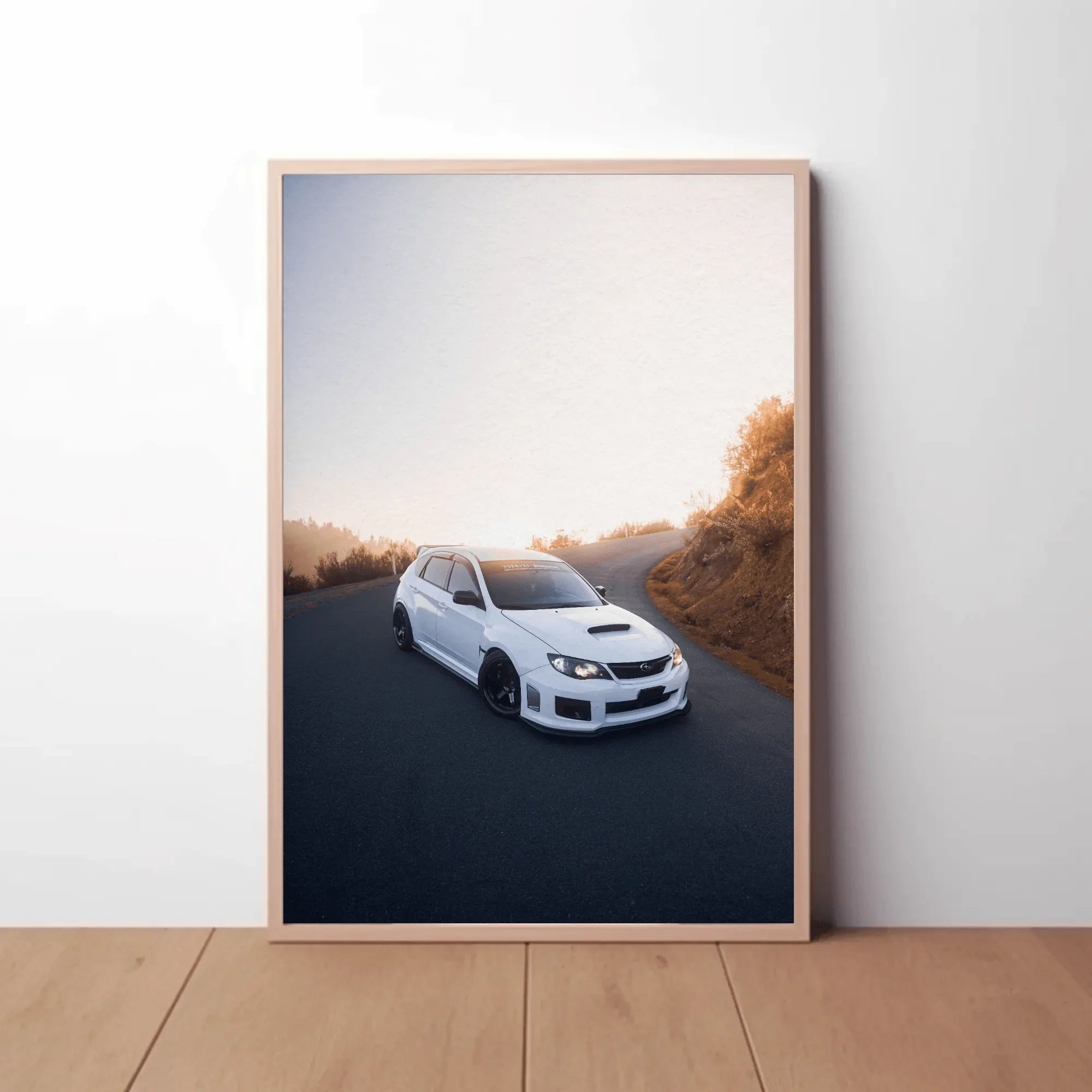Subaru WRX STI poster wall art featuring white car on winding road with soft sunset background.