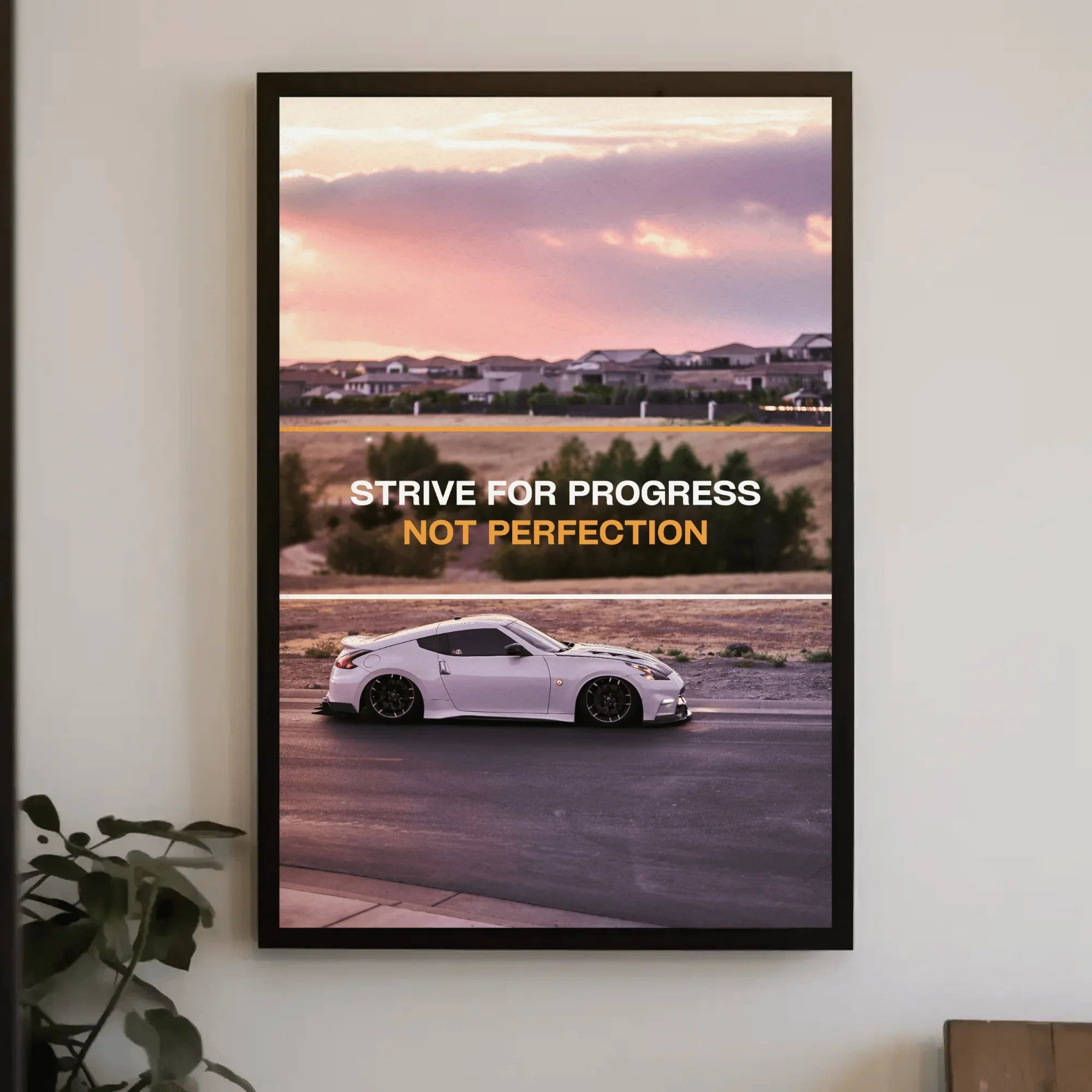 Motivational poster wall art with white Nissan 370z car and "Strive for progress not perfection" text against sunset.