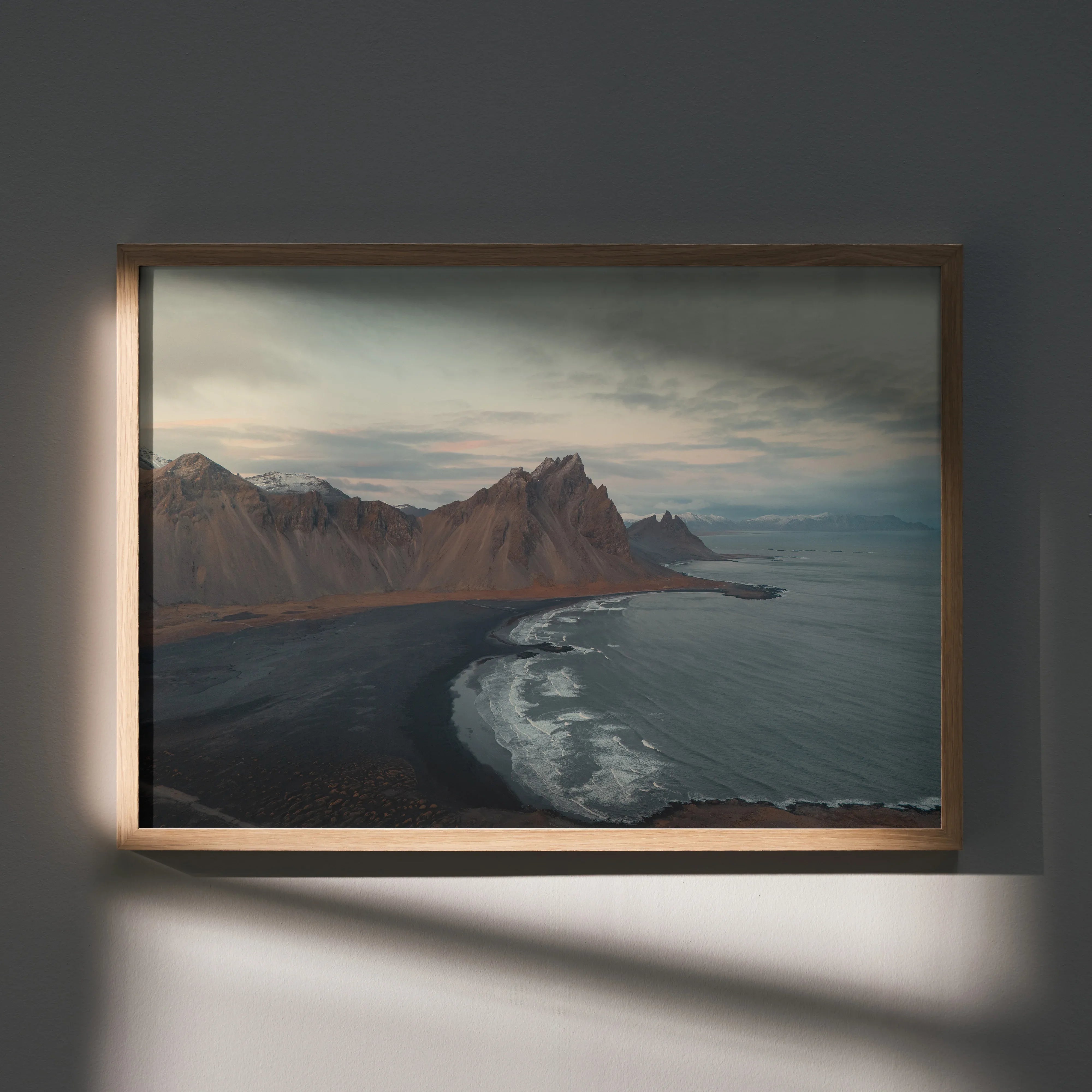 Majestic mountain range over dark shoreline with cloudy sky poster wall art in wooden frame.