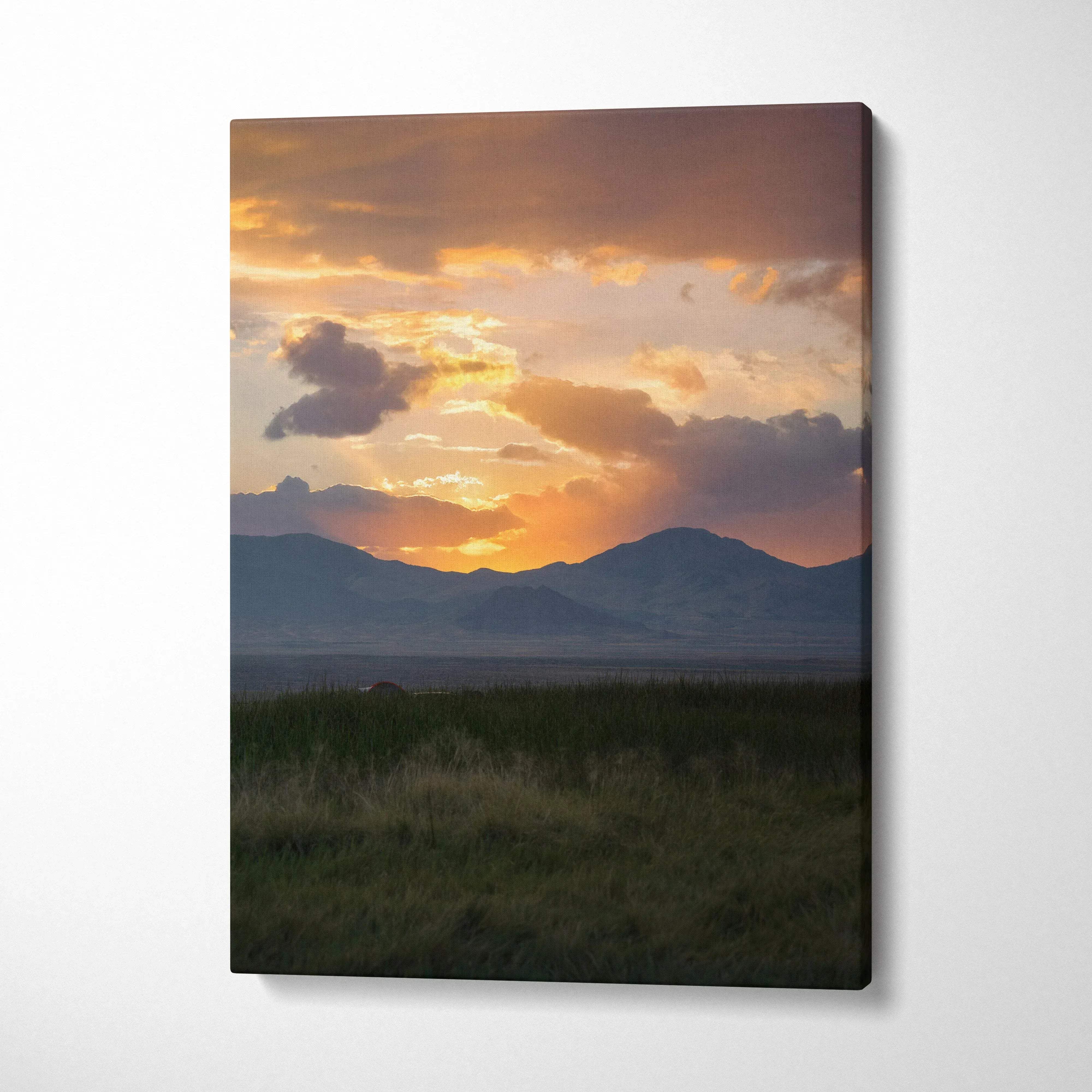 Canvas wall art featuring a vibrant sunset over mountain silhouettes with dark foreground grass.