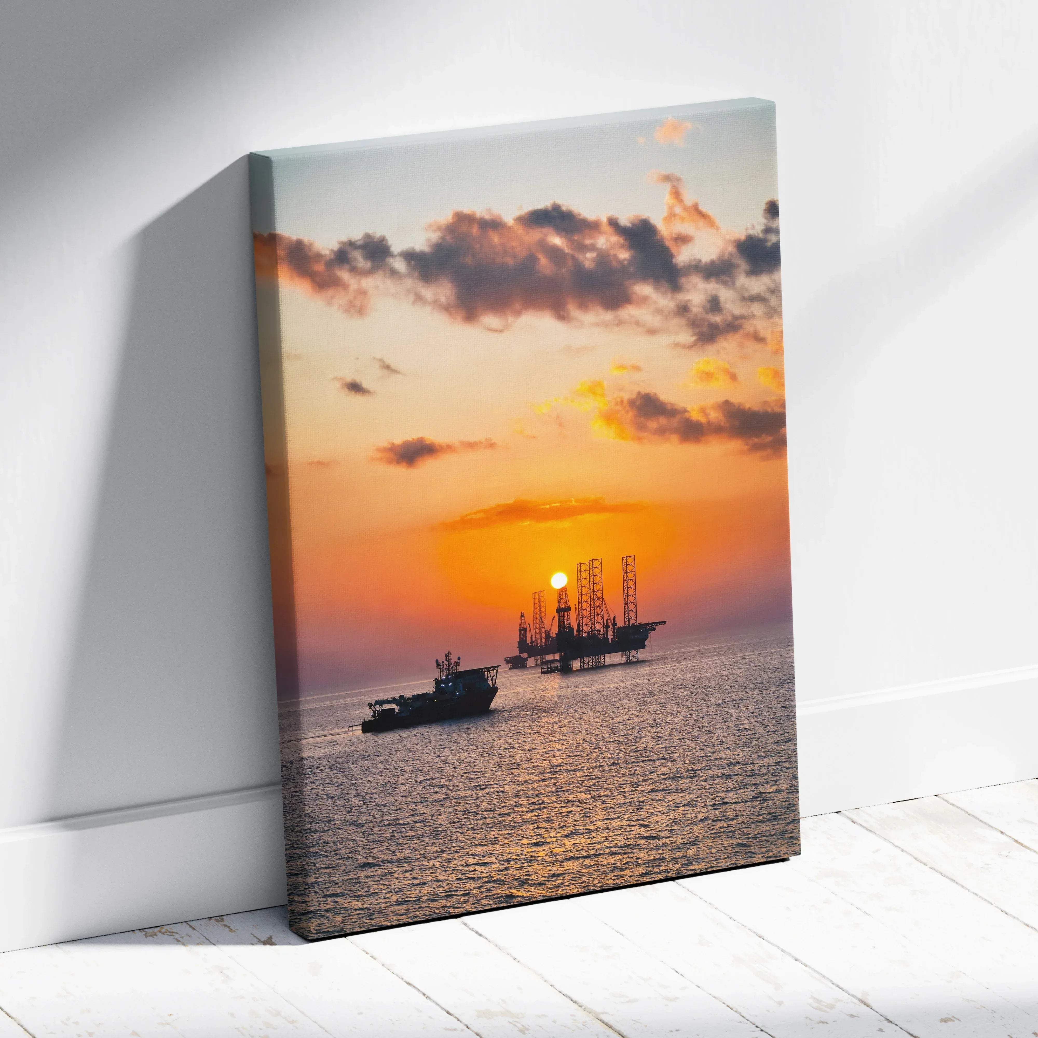 Canvas print featuring offshore oil rig silhouette against vibrant orange and pink sunset over ocean coastline