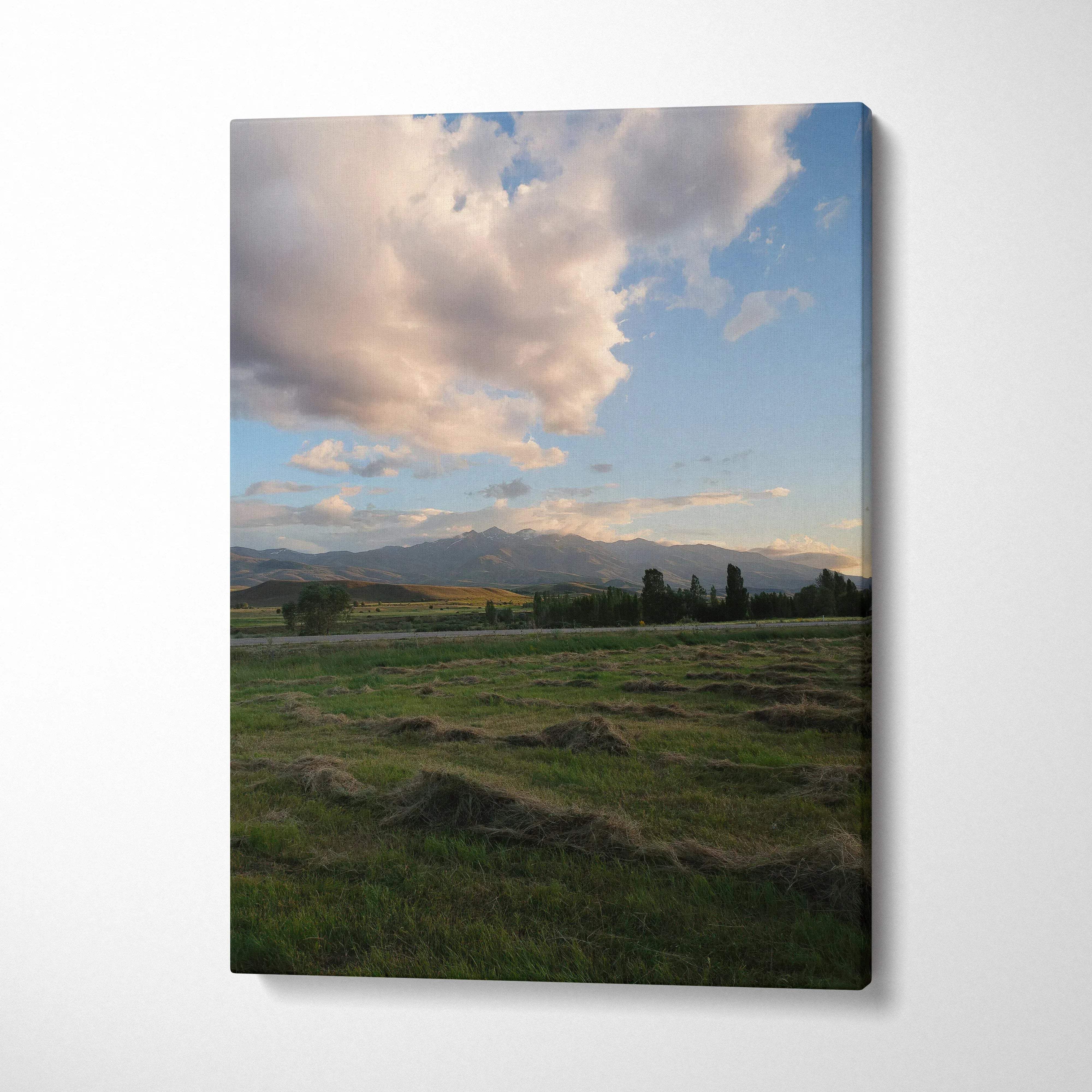 Canvas wall art featuring a serene mountain landscape under a glowing sunset sky with scattered clouds.