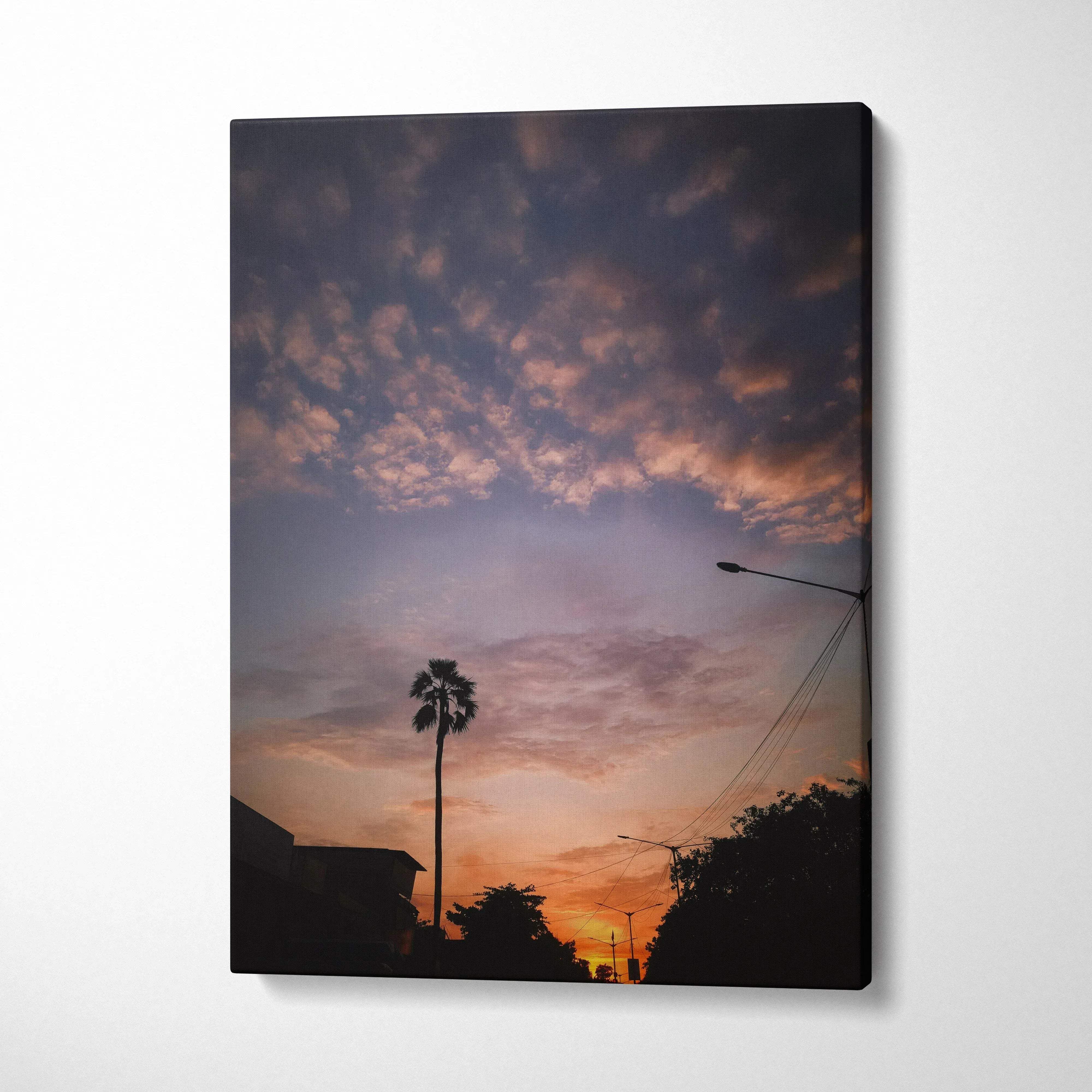 Vertical canvas wall art featuring a vibrant sunset sky with silhouetted palm trees and buildings.