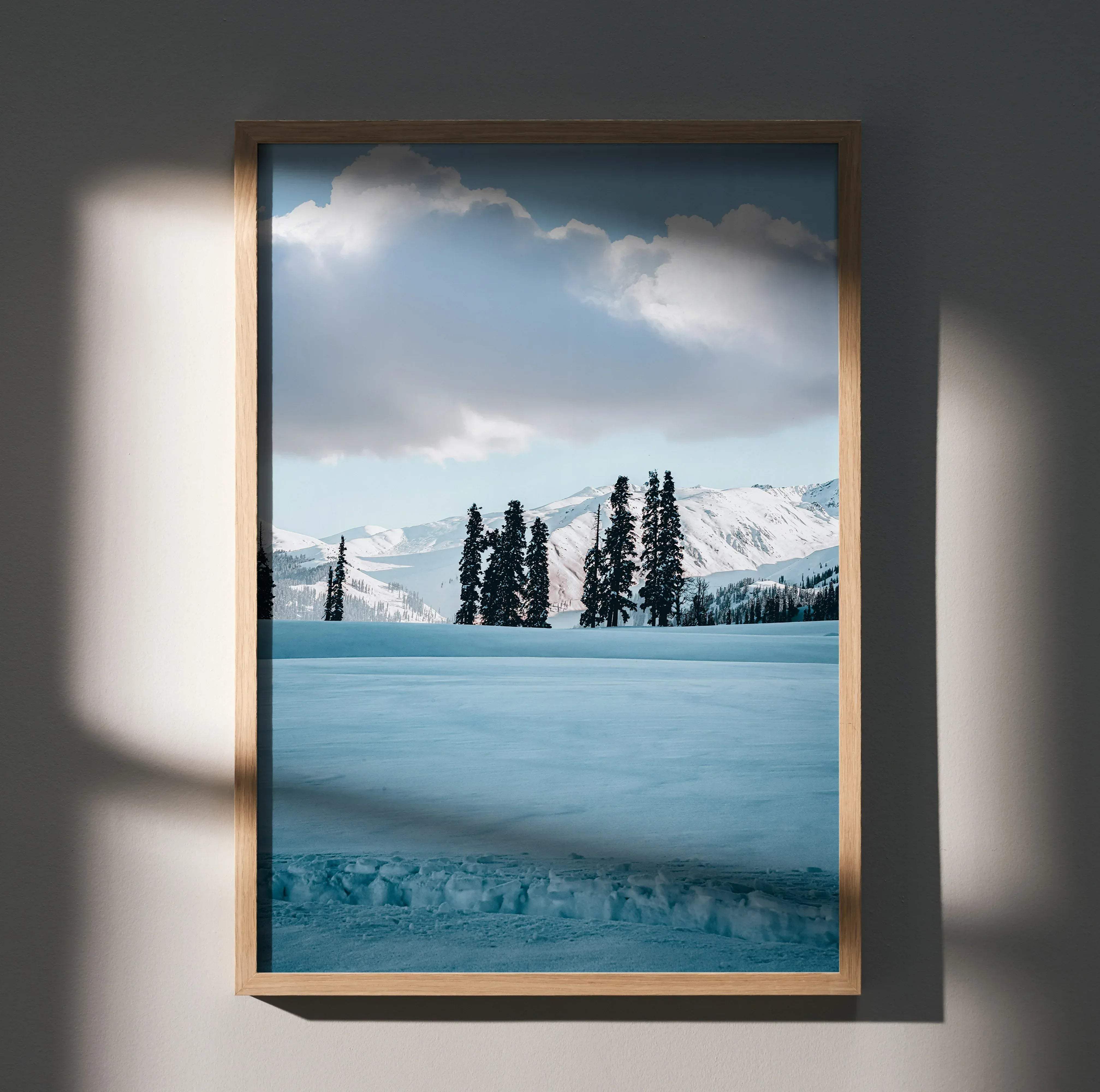 A framed vertical nature poster art featuring snow-capped mountains, evergreen trees, and a serene blue sky