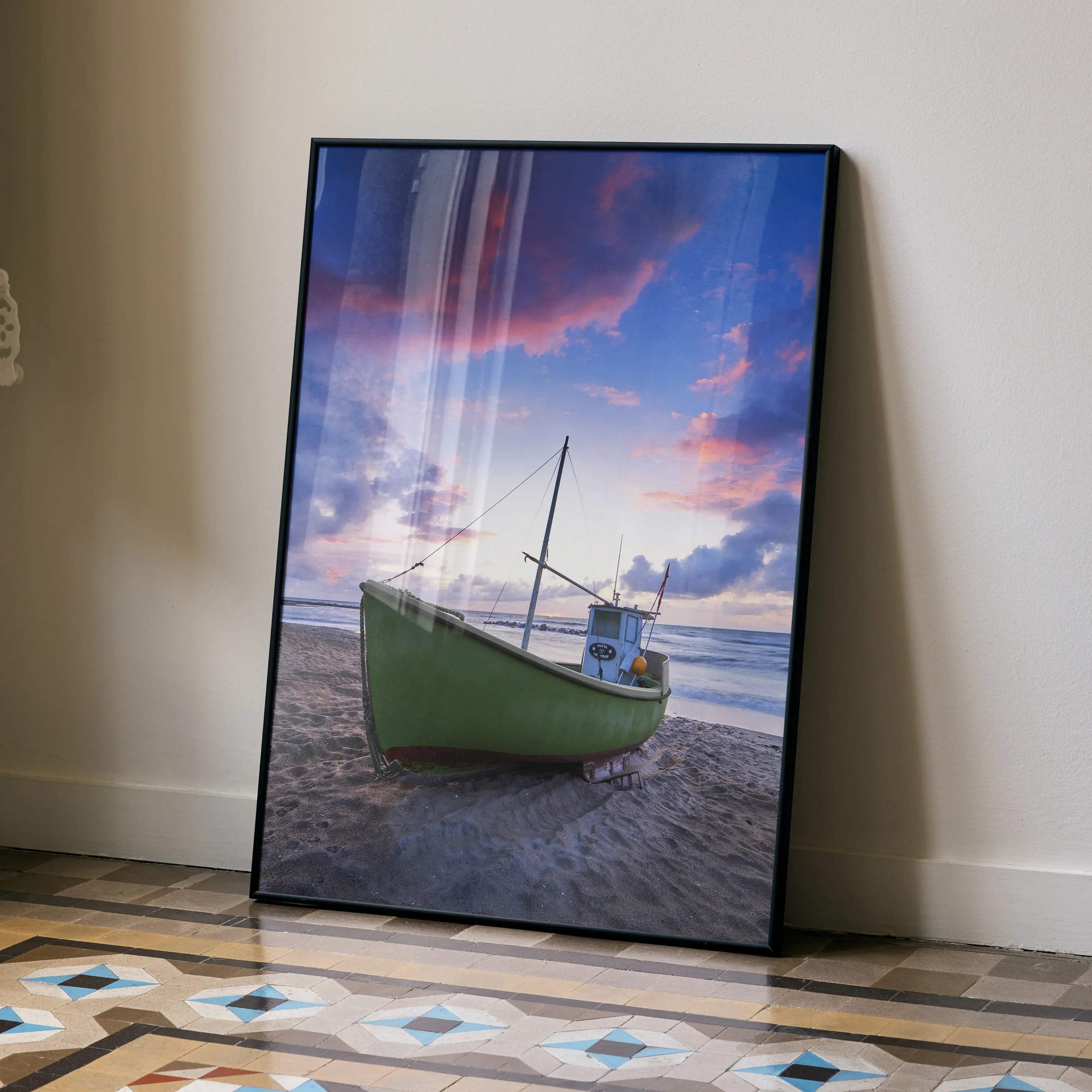 A framed canvas print of a green fishing boat on a sandy beach under a pink and purple twilight sky vertical poster