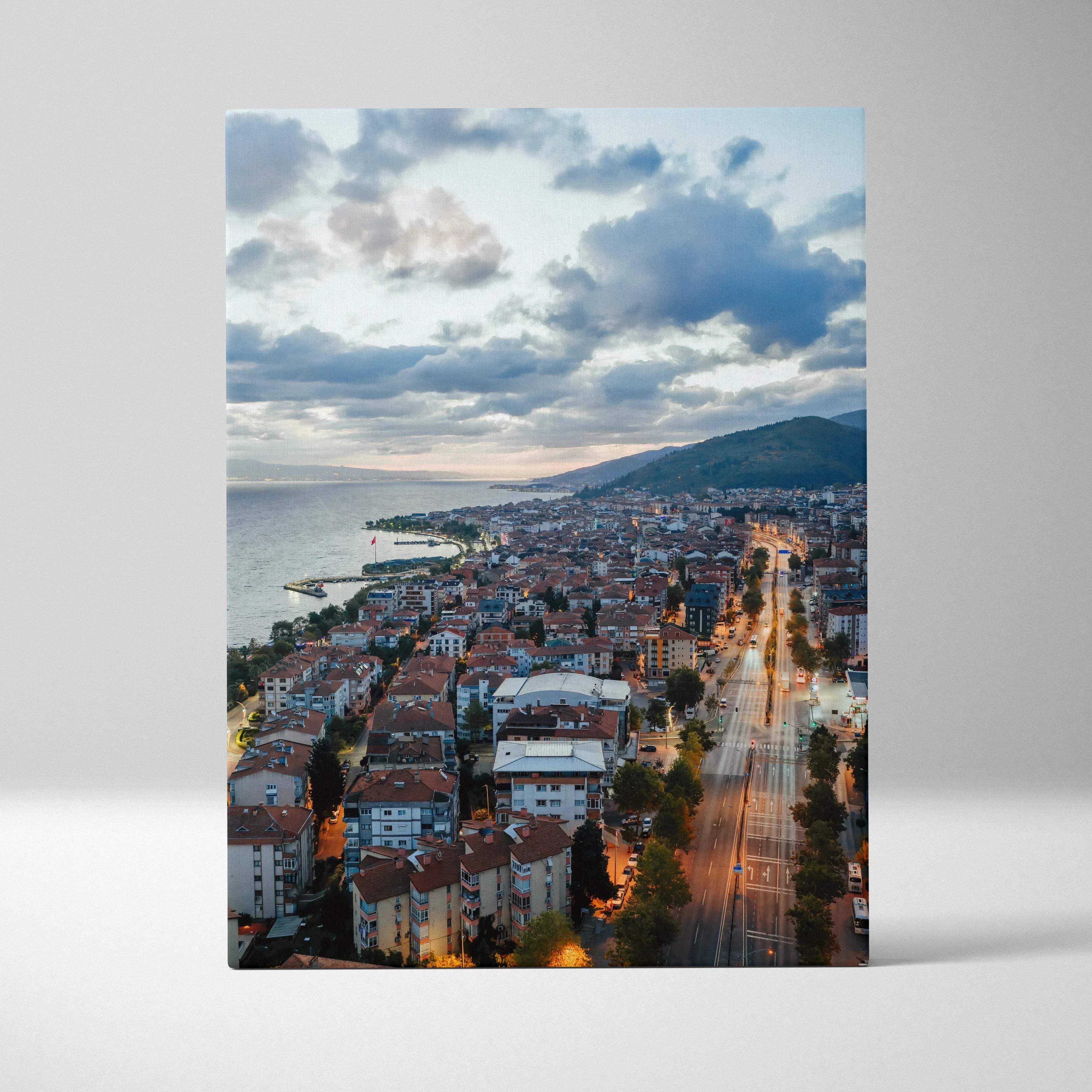 Aerial cityscape canvas print of a coastal town with red roofs and warm golden tones under a vibrant dusk sky