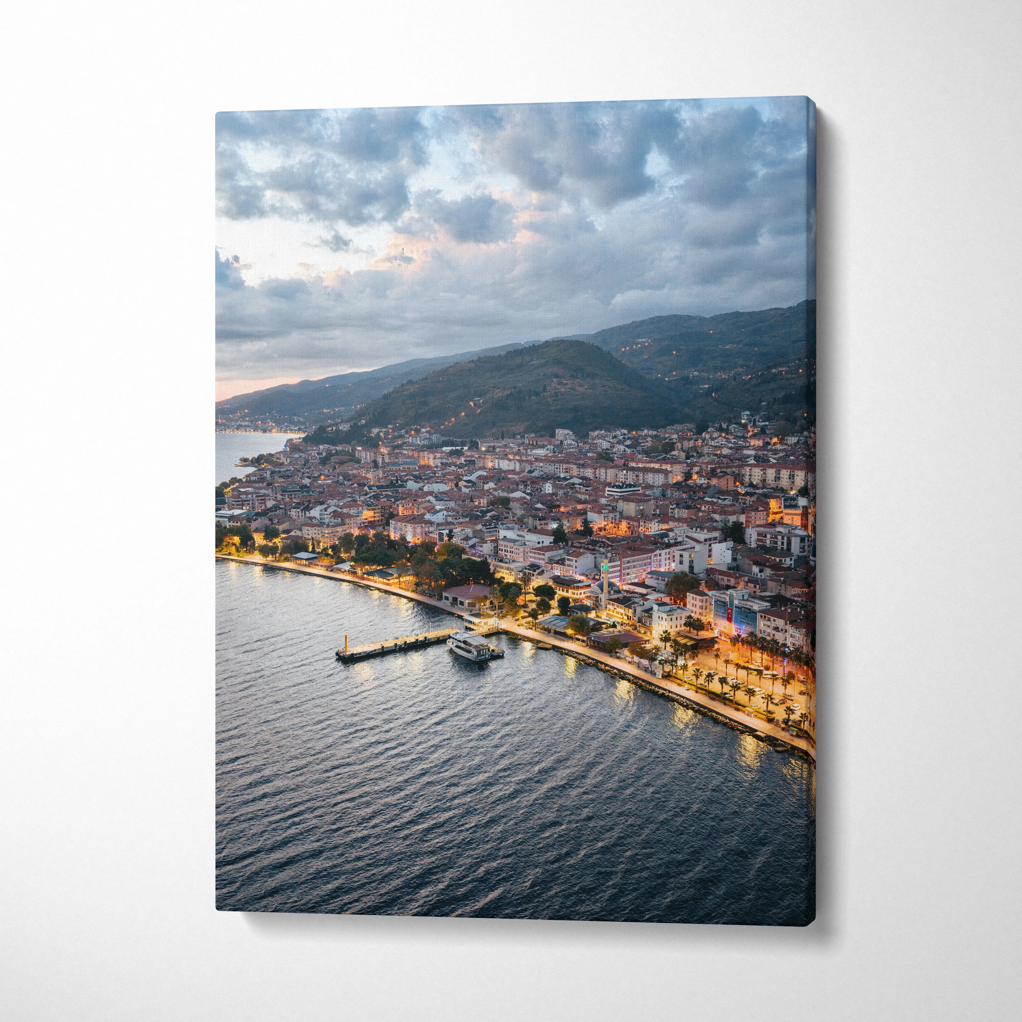 Canvas wall art print of a city at sunset with buildings along a waterfront under a cloudy sky.