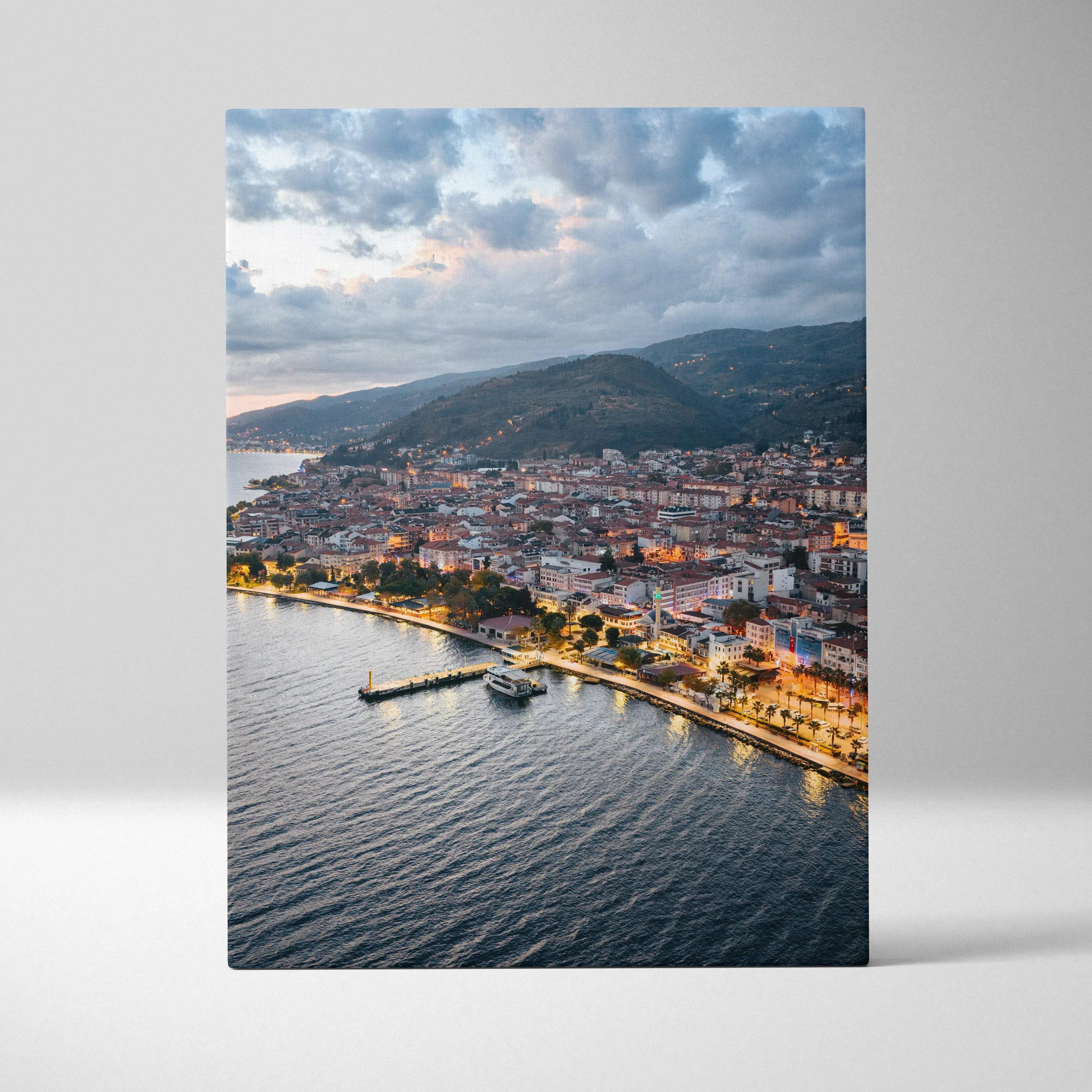 Aerial photograph print of a coastal town at dusk with illuminated streets on canvas wall art featuring warm golden hour glow