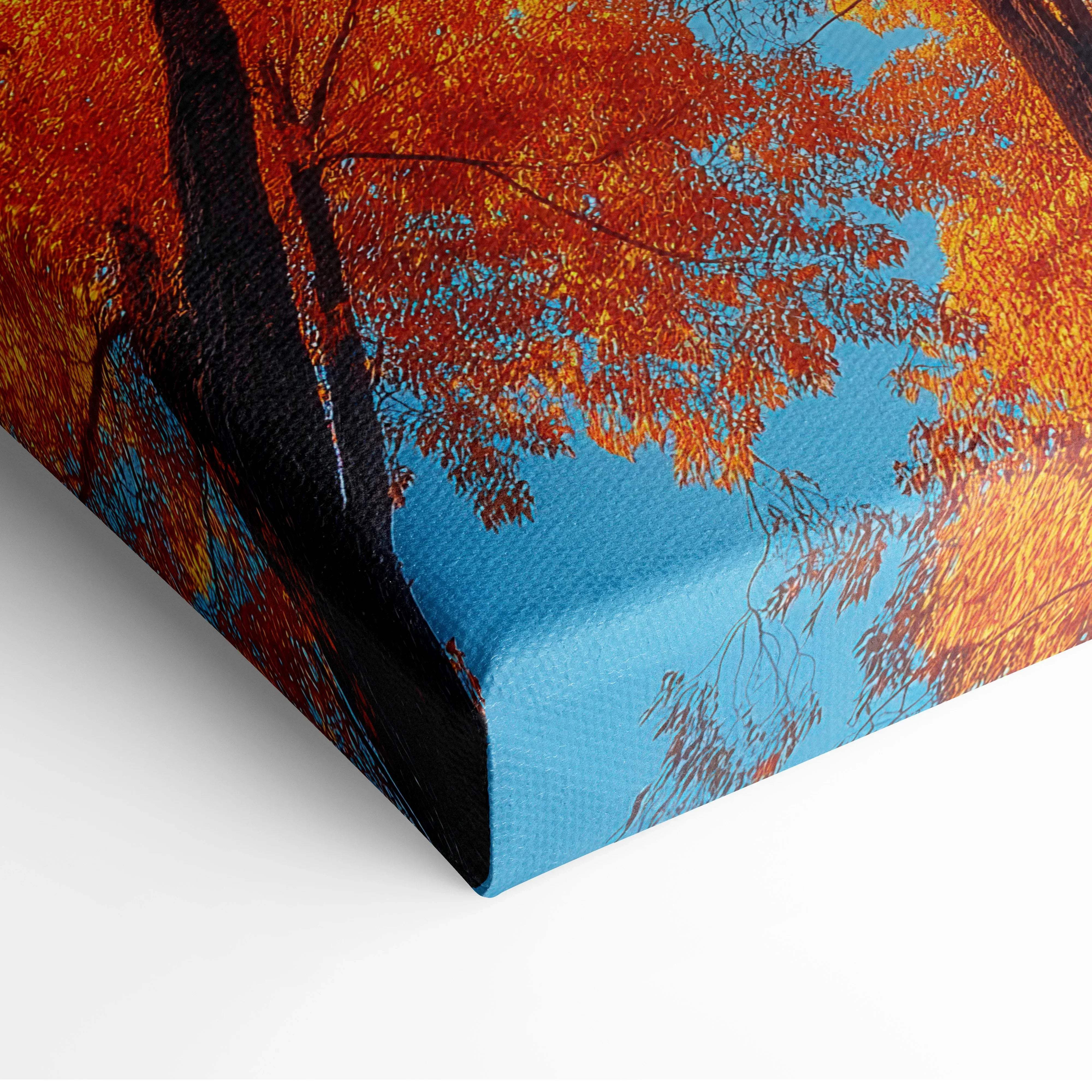 Canvas print of a vibrant autumn tree with fiery orange and red leaves against a bright blue sky wall art