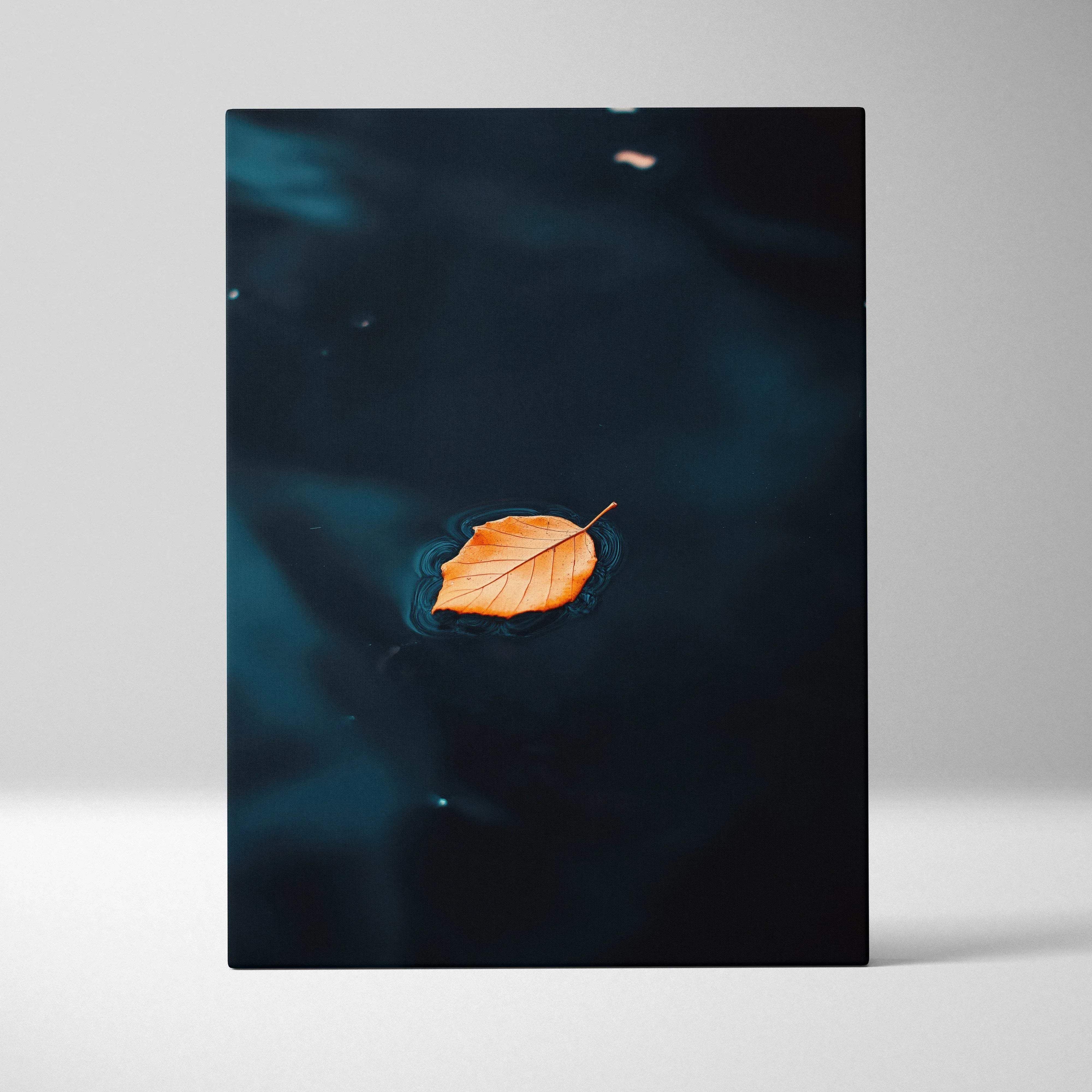 Minimalist autumn leaf floating on moody blue dark water canvas wall art featuring a vibrant orange leaf on teal water