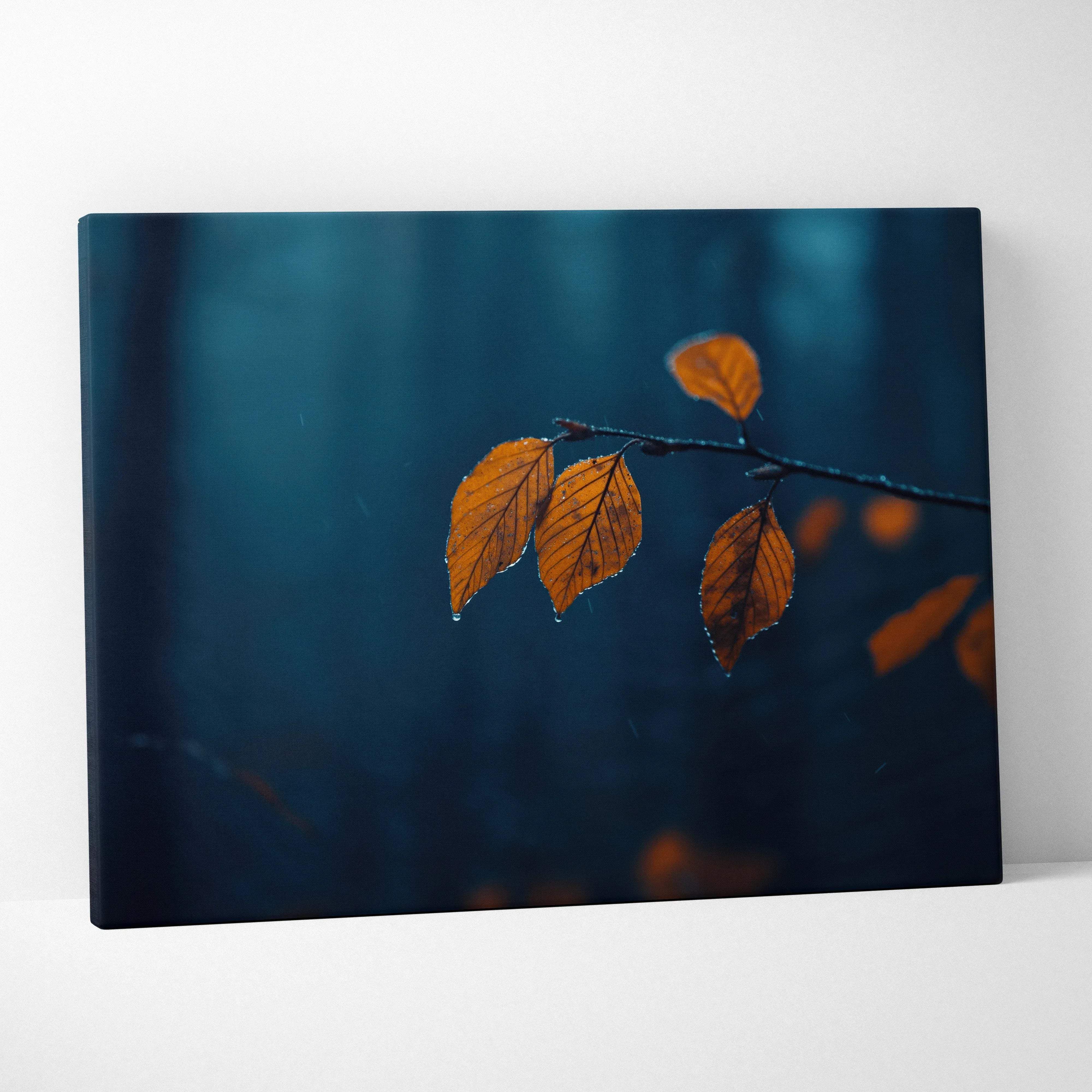 Canvas wall art featuring a minimalist branch with vibrant orange leaves on a moody blue blurred forest backdrop