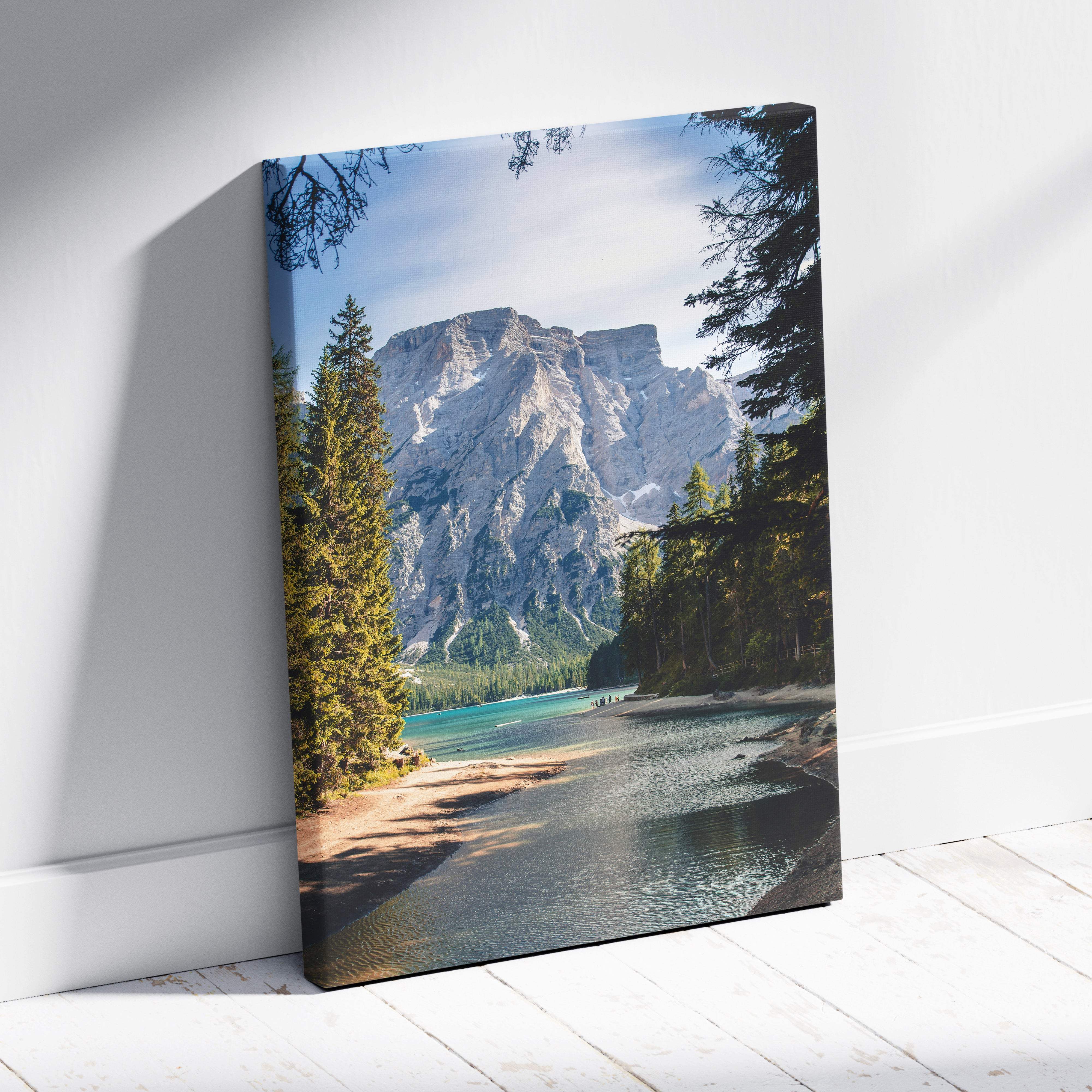 A framed canvas print of a green blue mountain lake with evergreen trees and rugged peaks for serene nature decor