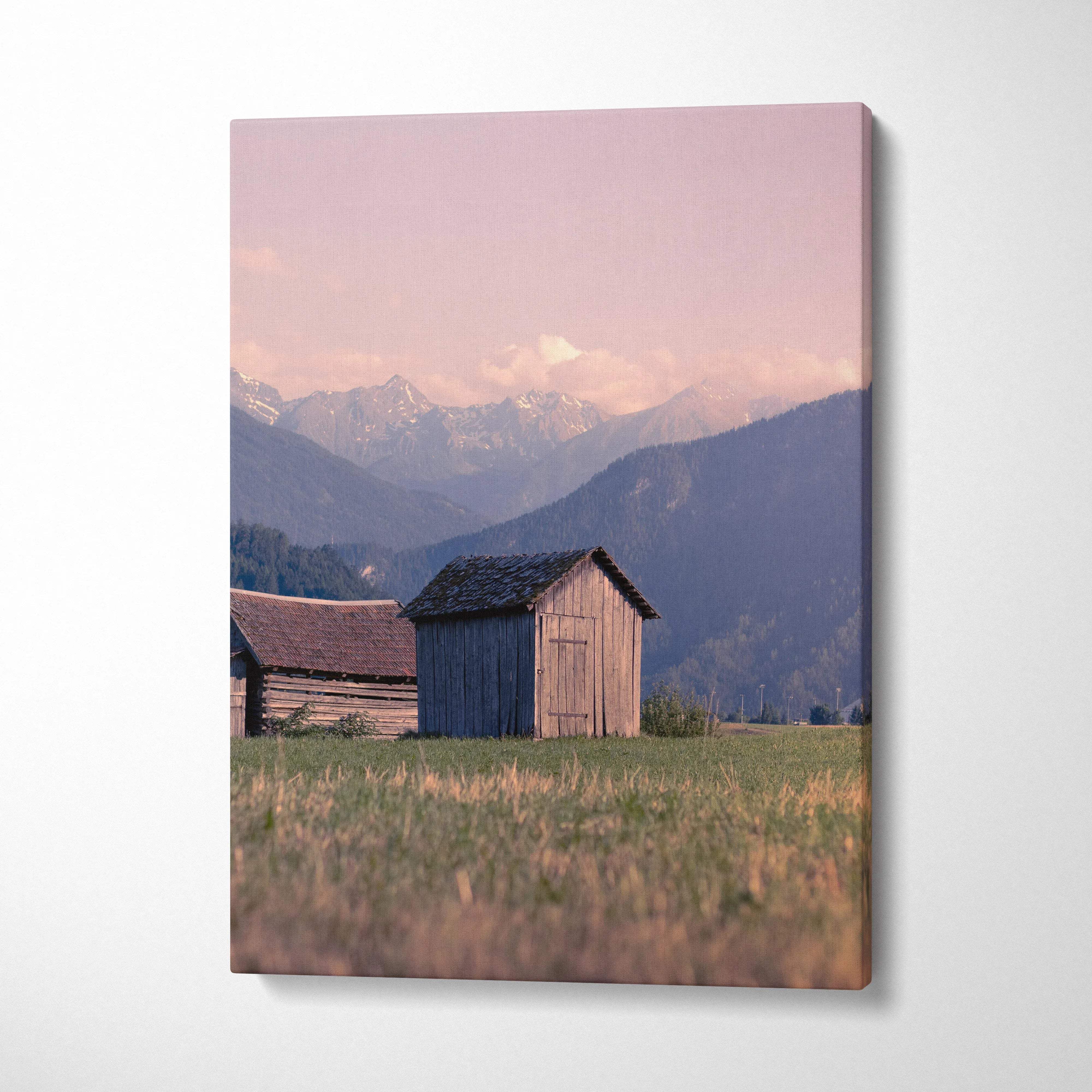 Canvas wall art featuring rustic buildings with golden sunlight on mountains at sunset.