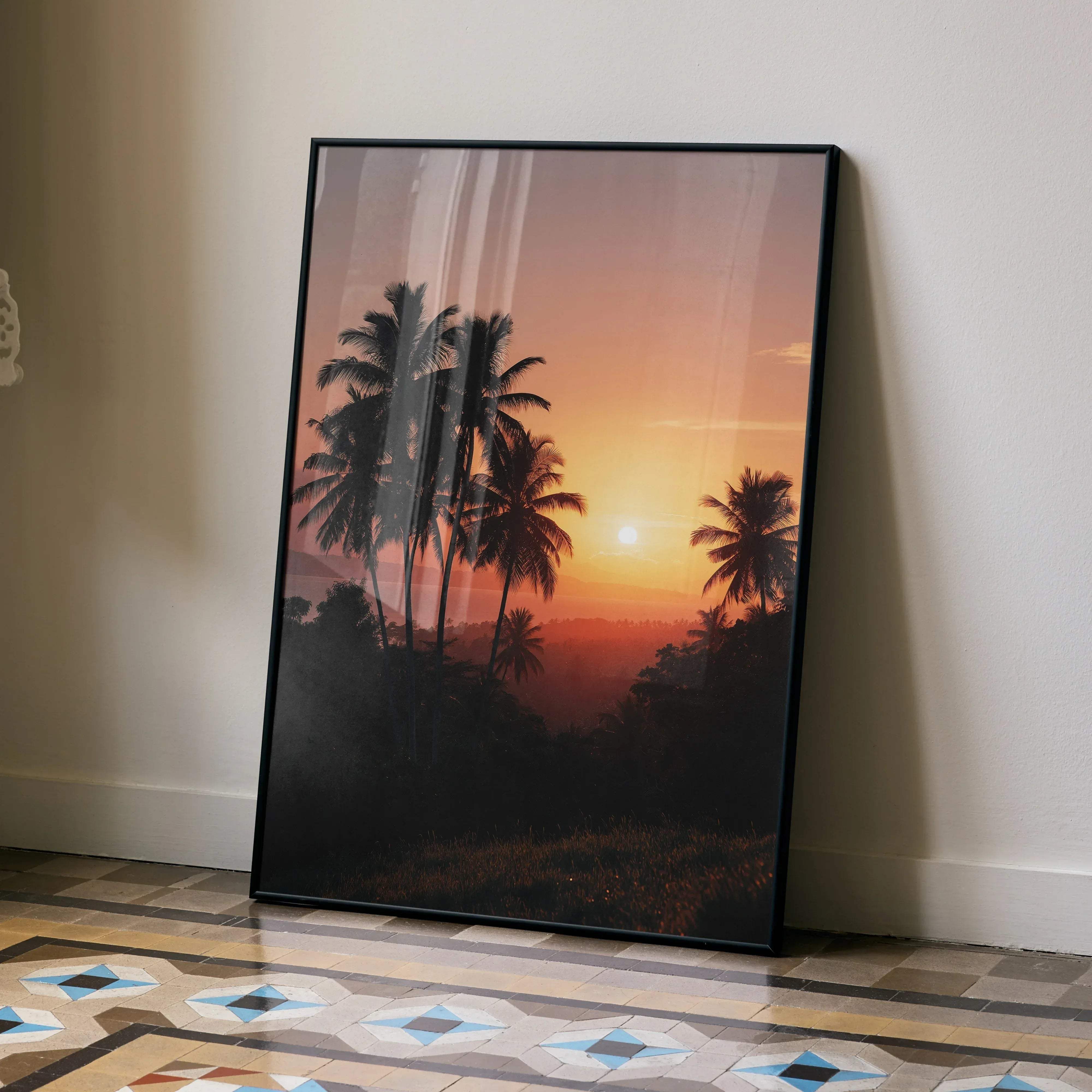 Black-framed vertical wall art poster of a tropical beach sunset with silhouetted palm trees on an orange and pink sky