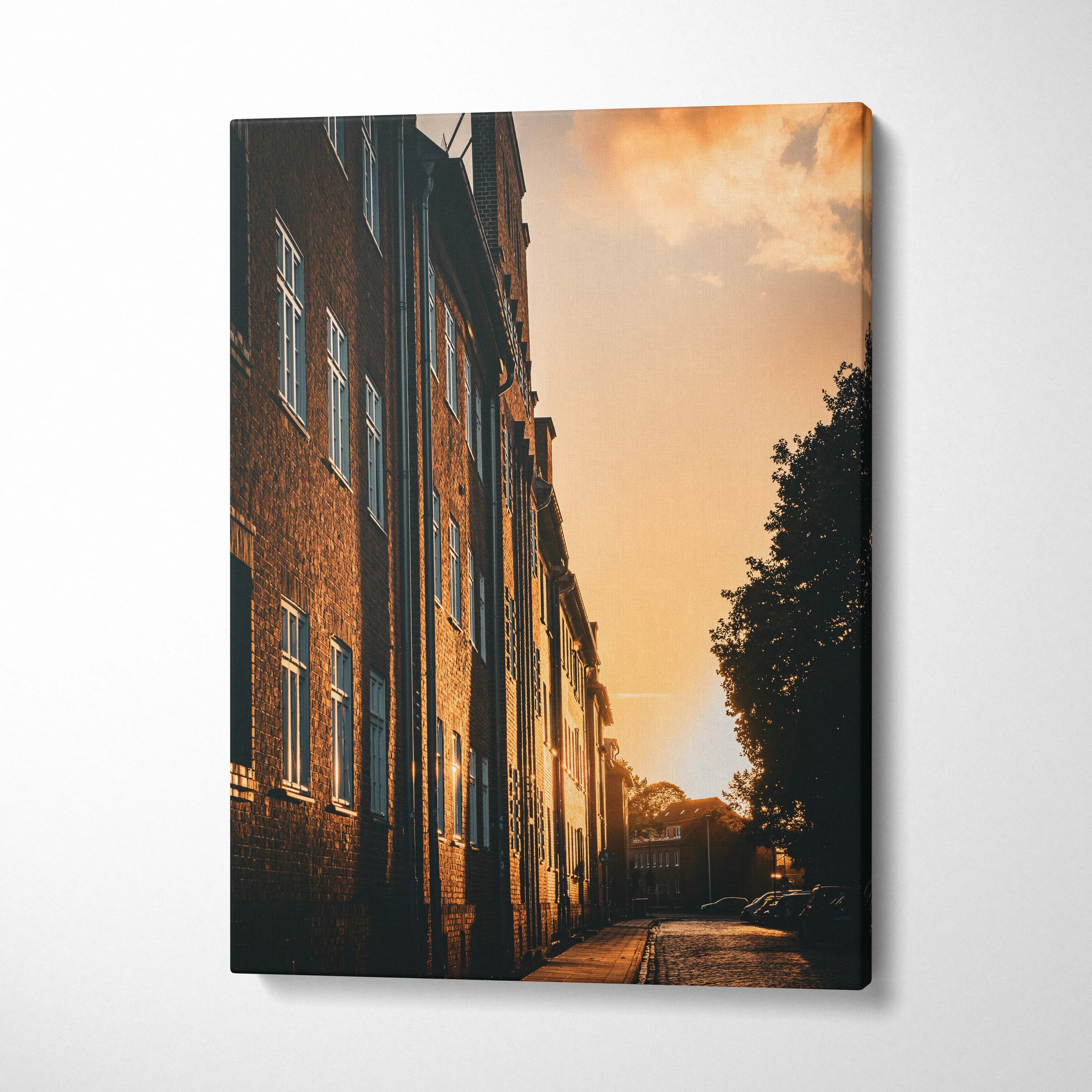 Sunset-lit city street with brick buildings on canvas wall art.