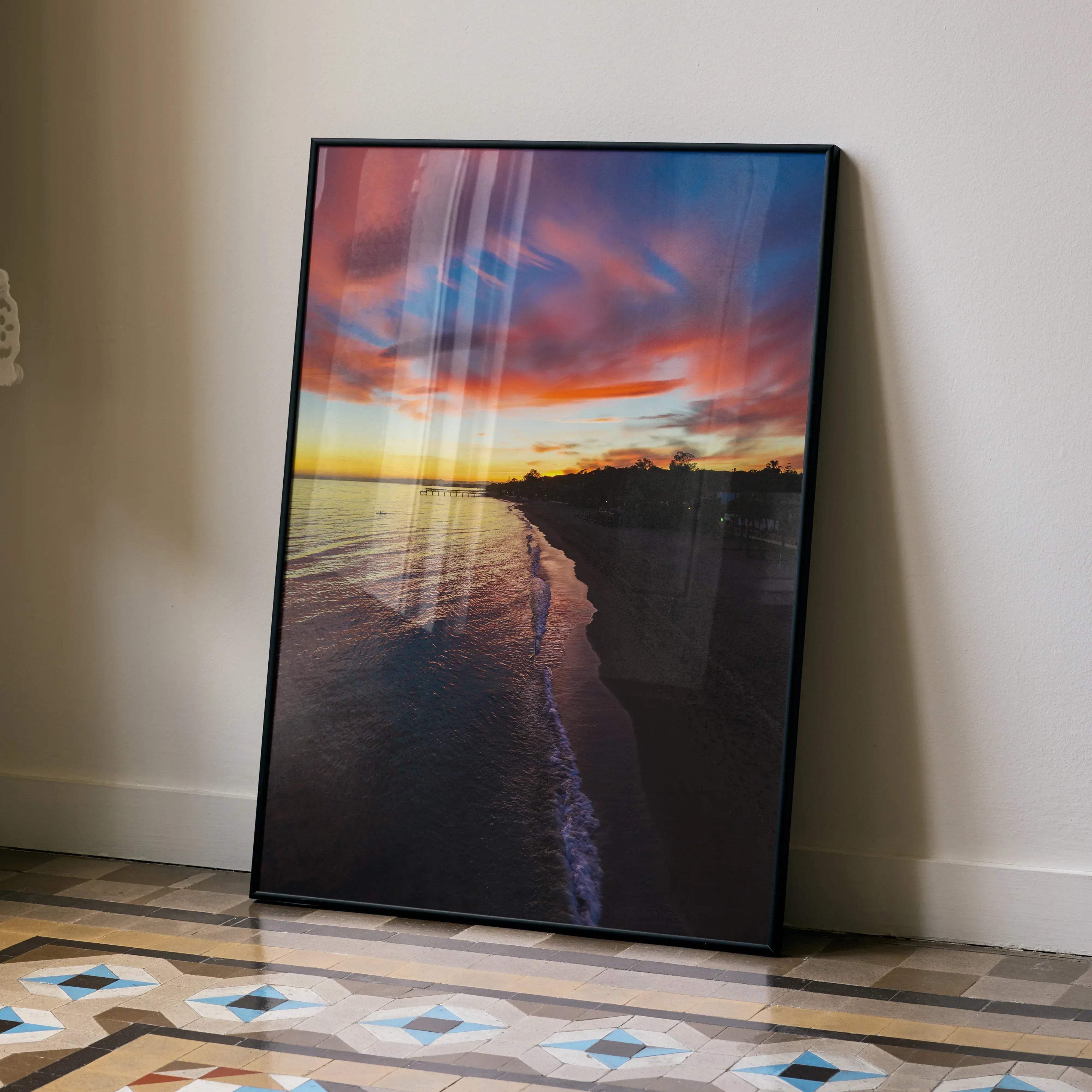 Black-framed canvas print of a vibrant beach sunset with pink orange and purple clouds reflecting on ocean water vertical poster
