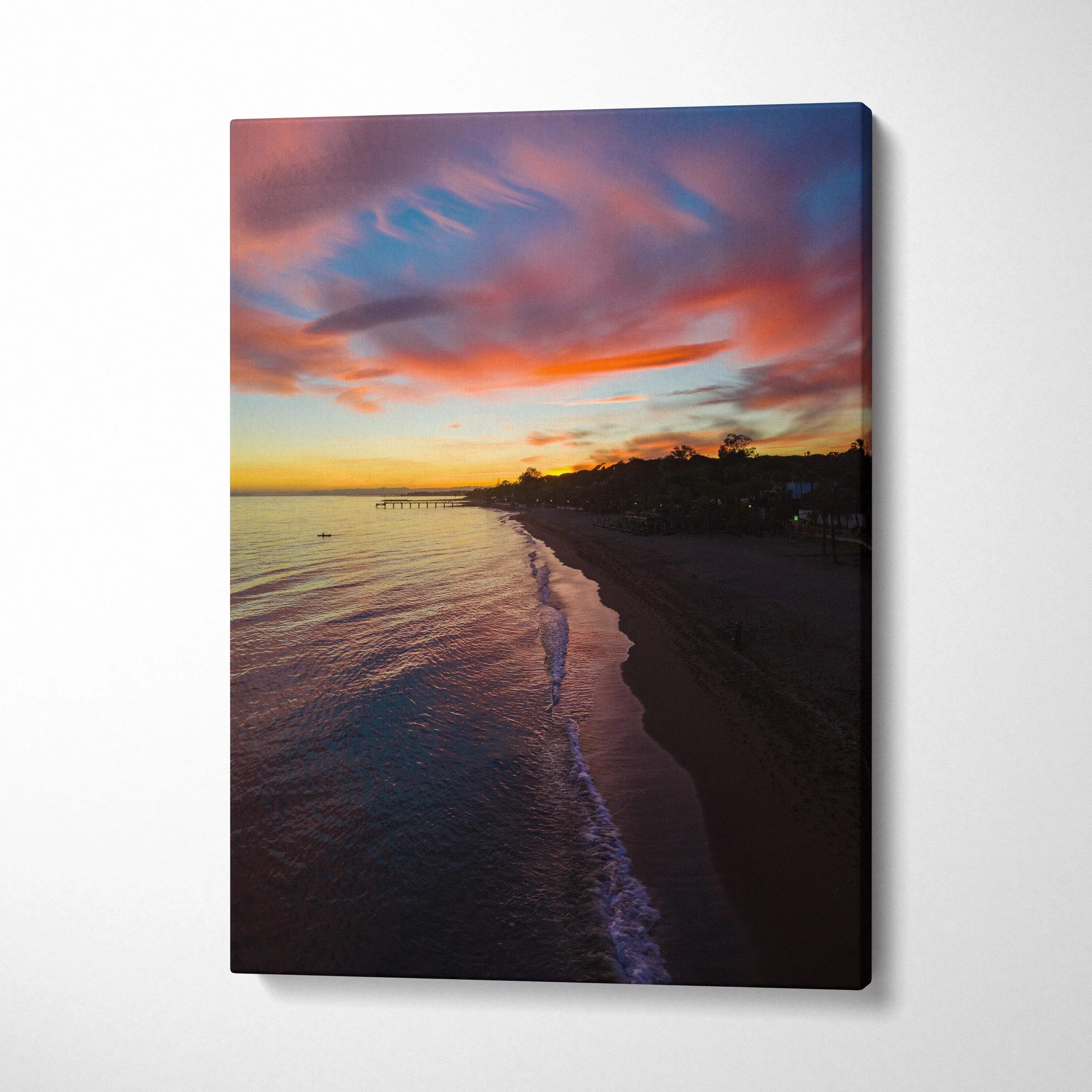 Canvas wall art featuring a vibrant beach sunset with colorful clouds over calm water and dark shoreline.