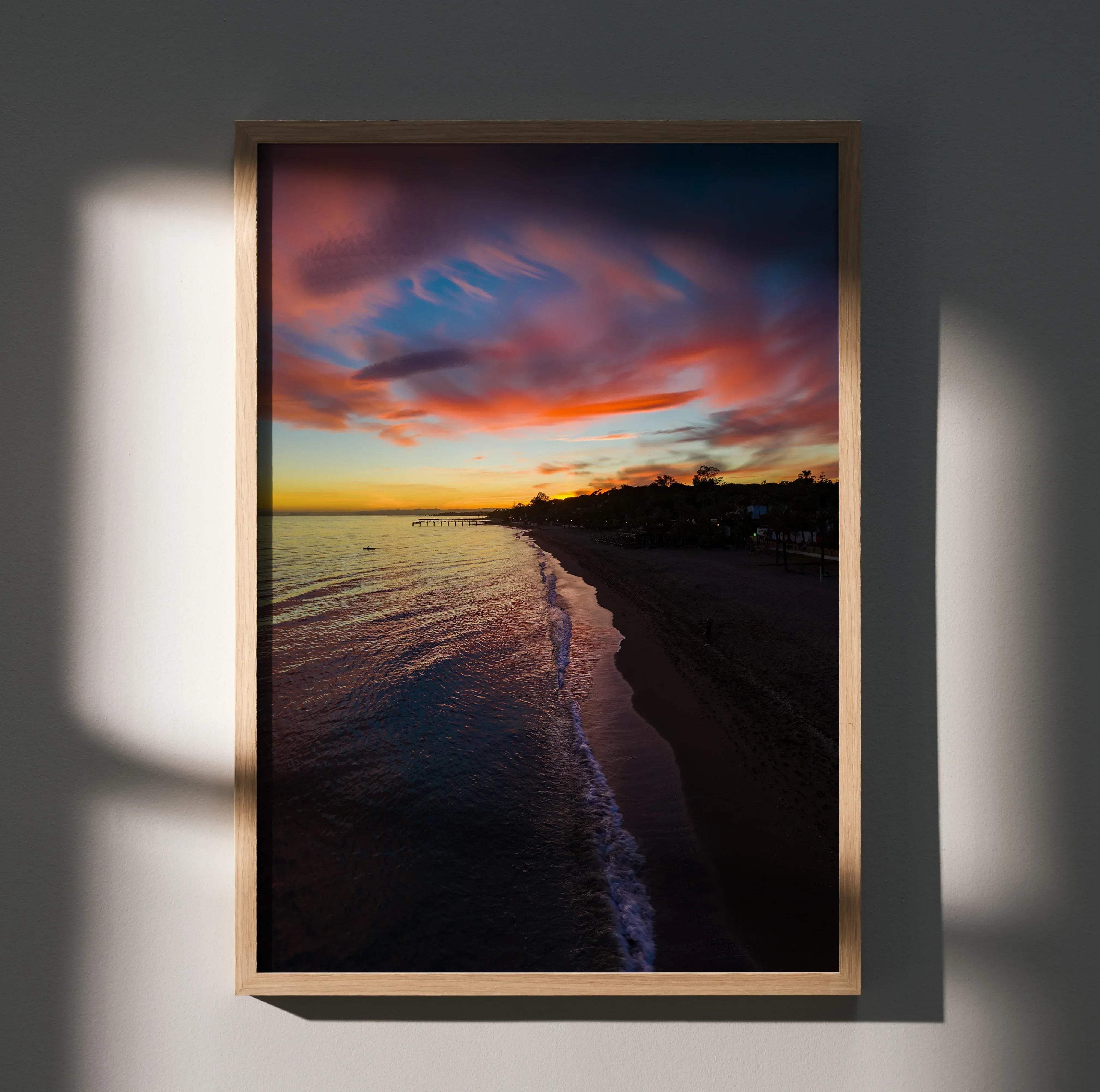 A framed vibrant beach sunset poster with pink orange and purple clouds over the ocean for wall art decor vertical