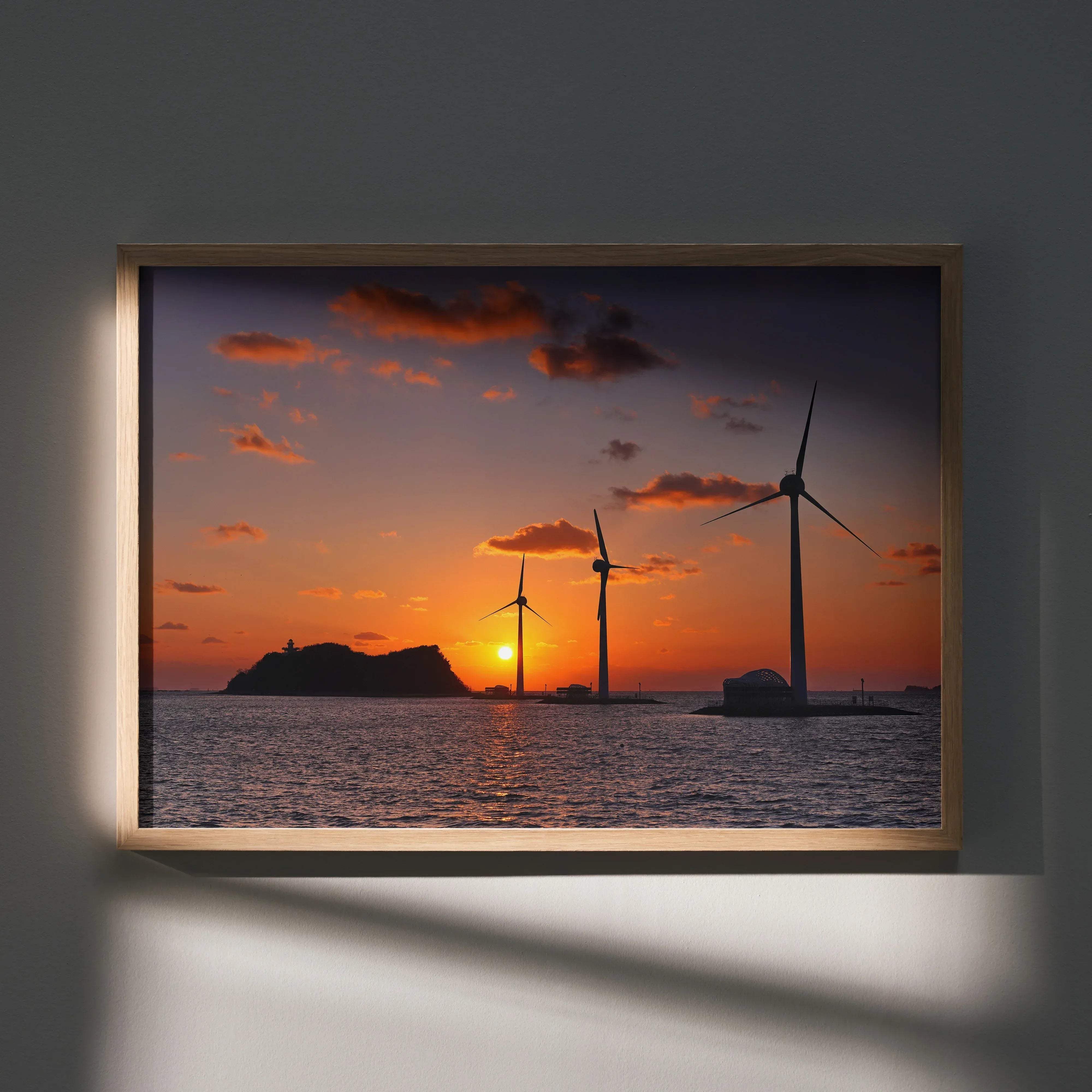 Serene ocean sunset art print wall decor featuring a framed photo of three wind turbines silhouetted at sunset