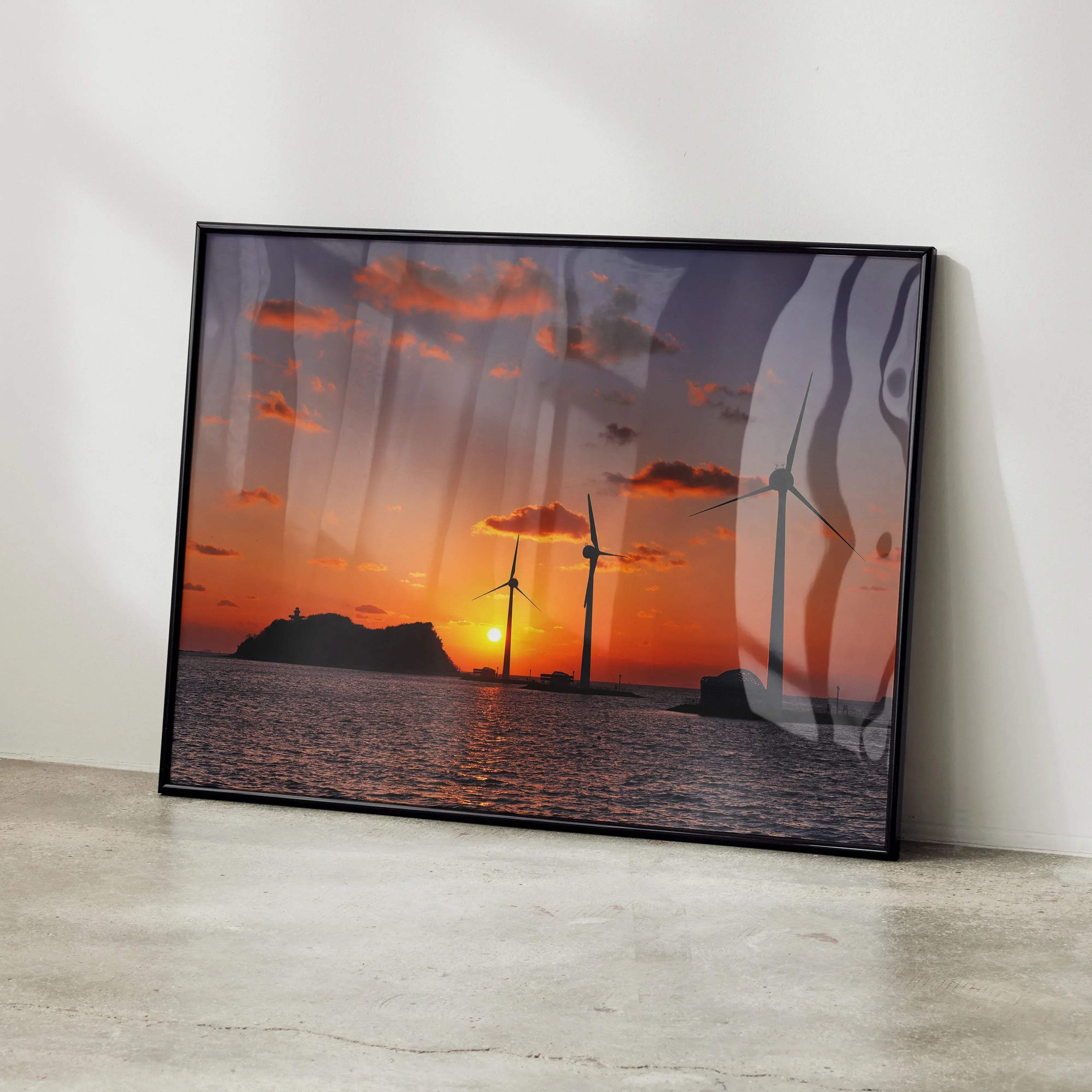 Black-framed serene ocean sunset art print wall decor featuring wind turbines against orange and purple sky over water
