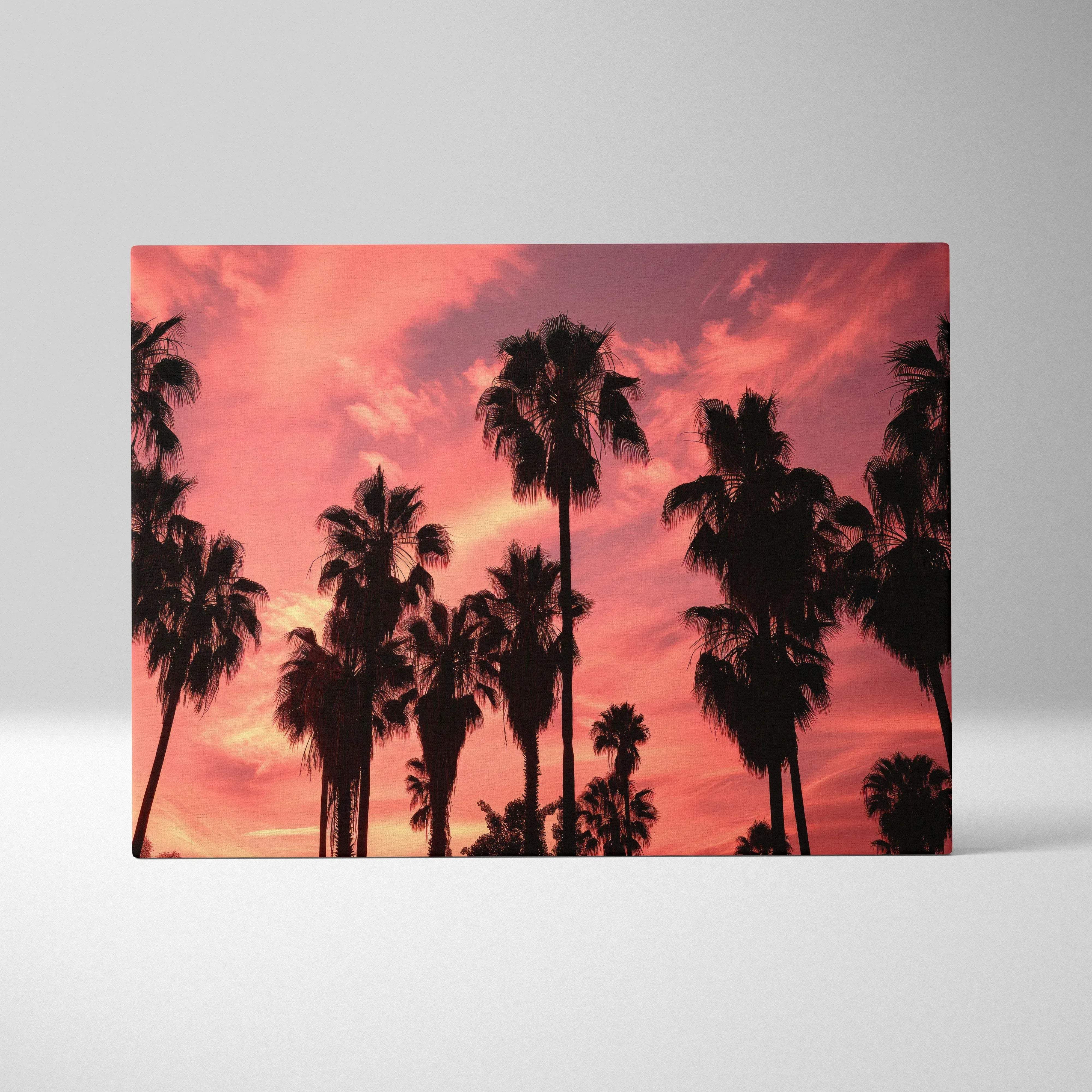 Rectangular canvas wall art featuring silhouetted palm trees against a warm amber to coral sunset sky