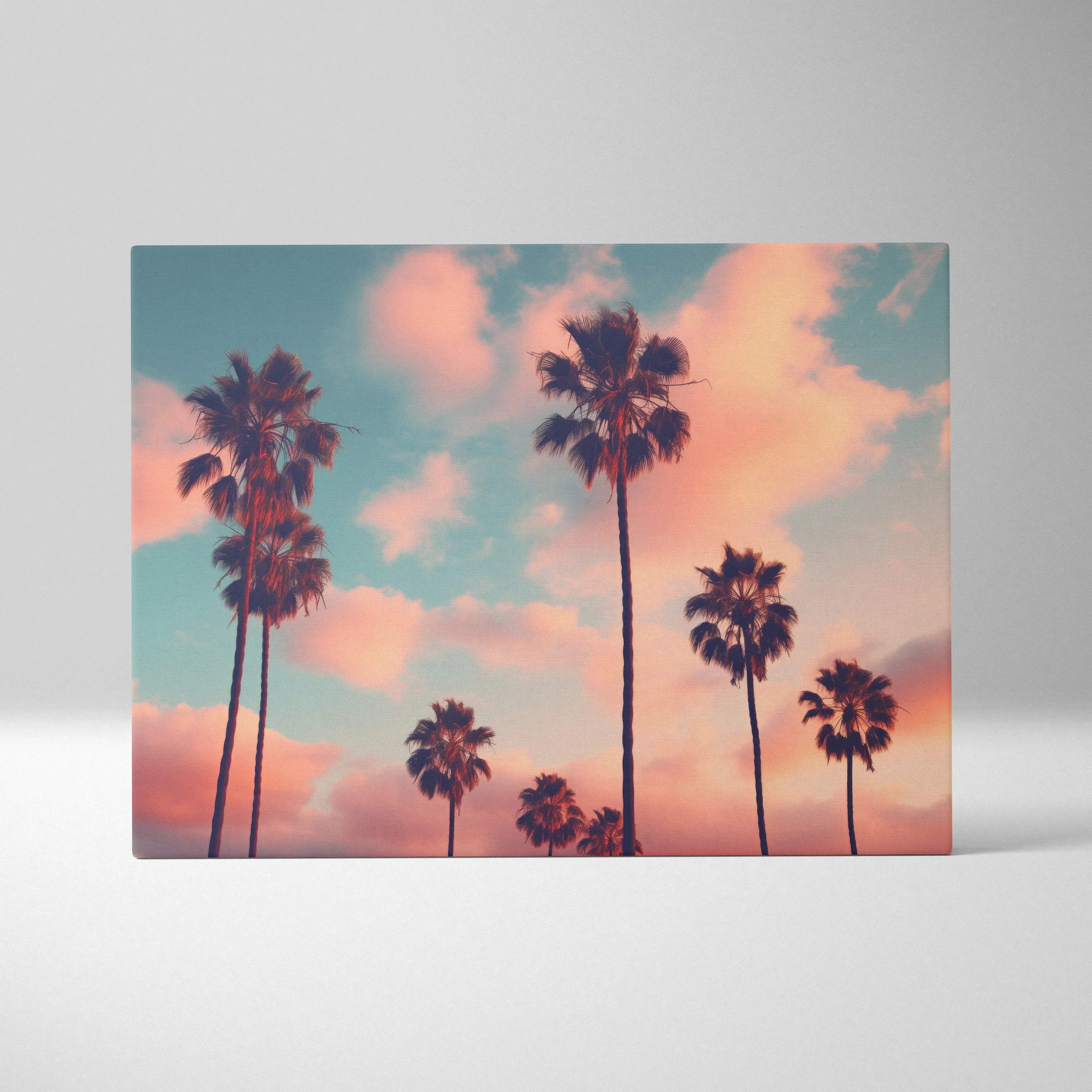 Rectangular canvas wall art featuring silhouetted palm trees against a warm coral sky with soft pastel pink and teal clouds