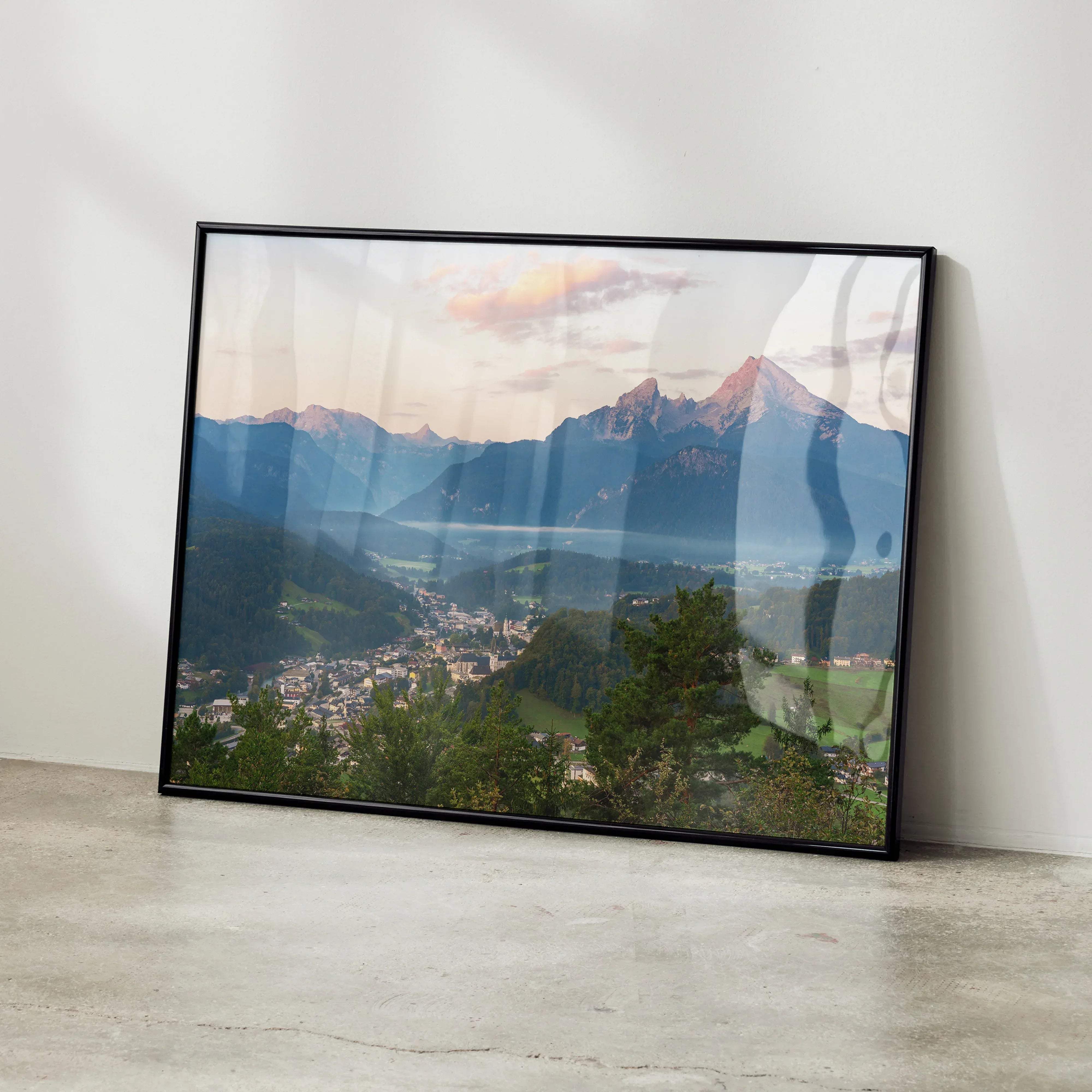 Black-framed stunning mountain sunset wall art print showing snow-capped peaks lush valleys and a town below
