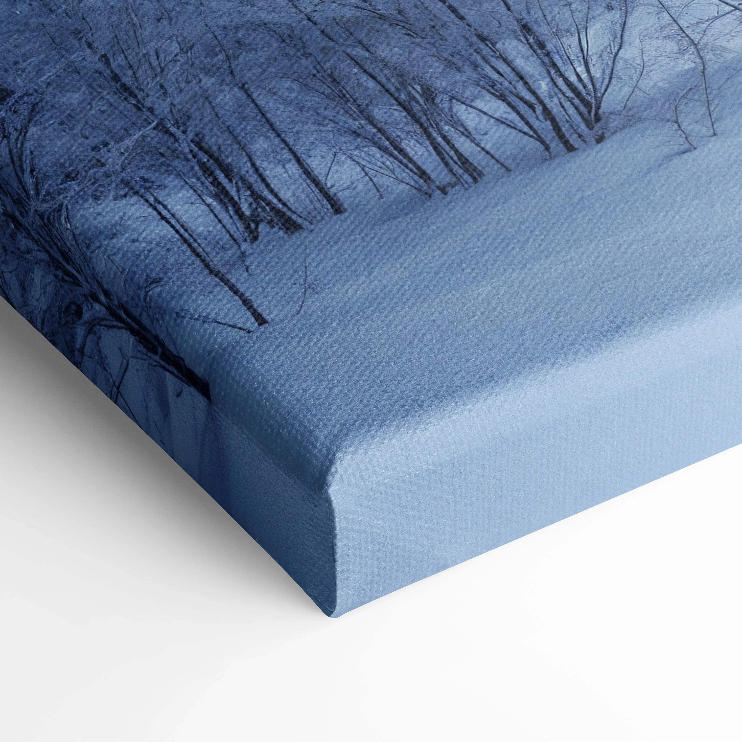 Blue snowy forest canvas print with dark tree silhouettes and sunbeams