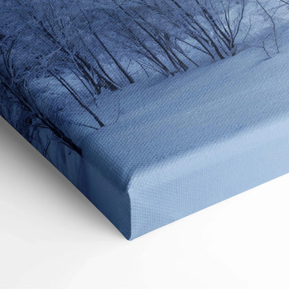Blue snowy forest canvas print with dark tree silhouettes and sunbeams