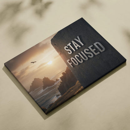 Black motivational canvas art with Stay Focused in silver on sunset cliff by sea