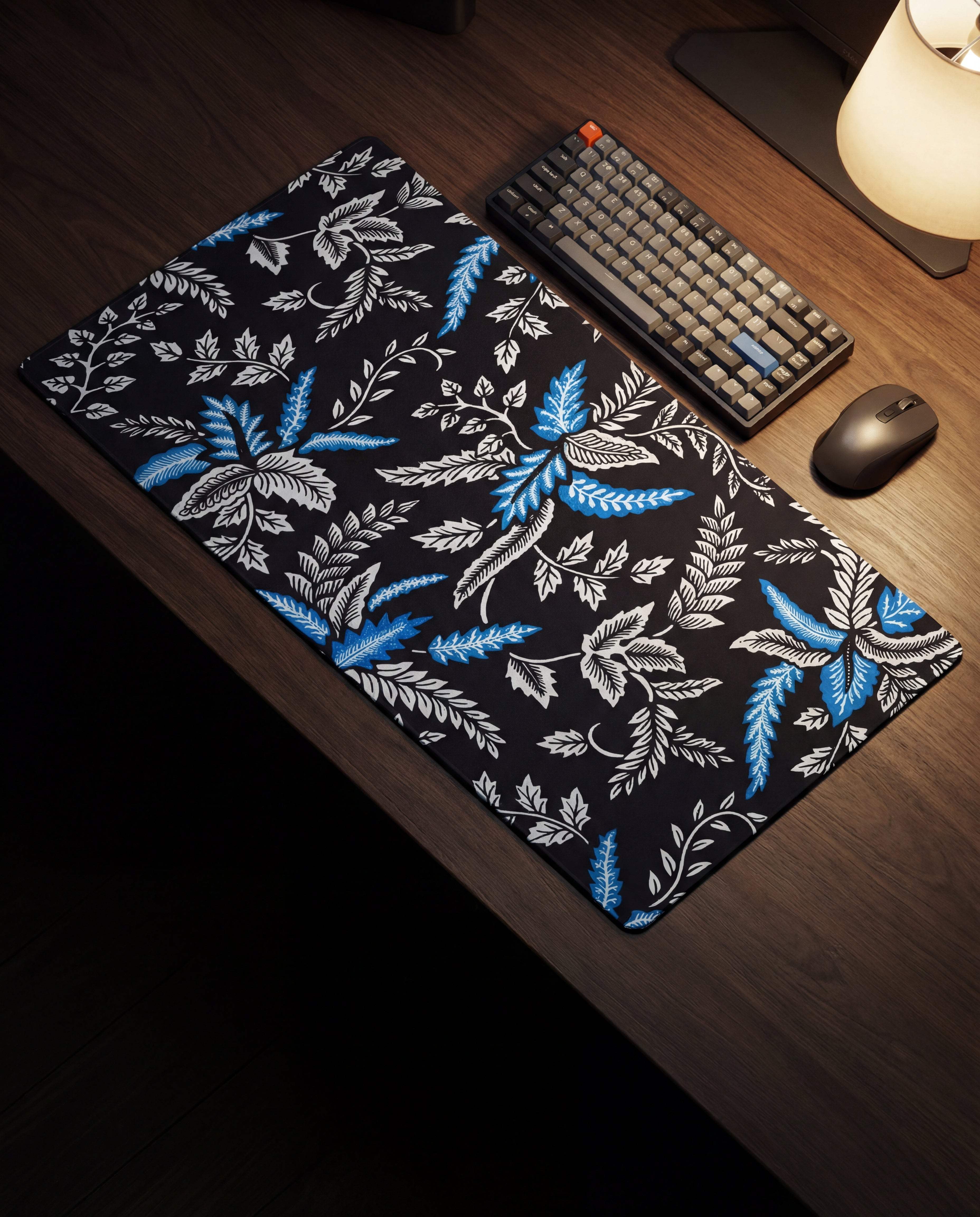 Black mousepad with a vibrant blue and white botanical leaf pattern.