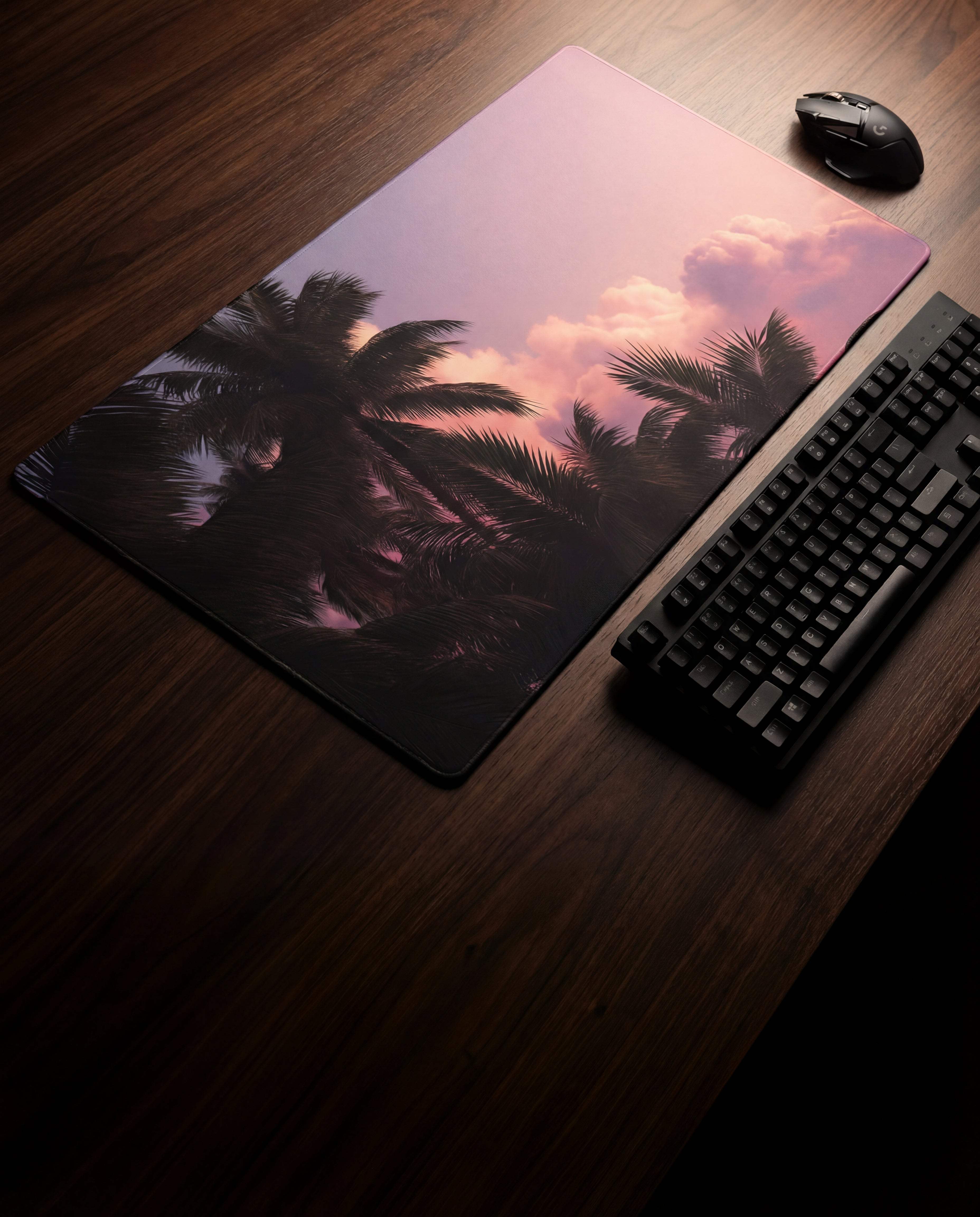 A rectangular mousepad featuring a vibrant sunset scene with silhouetted palm trees against pink and purple clouds.