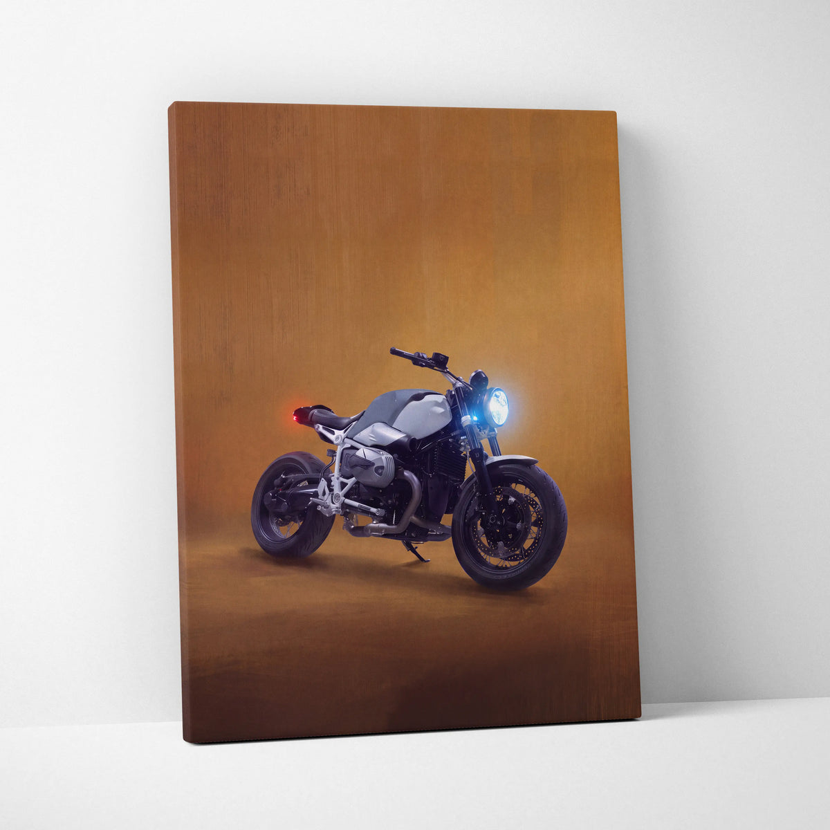 Canvas print of a sleek matte black and silver bmw r ninet motorcycle with blue headlights on amber background wall art