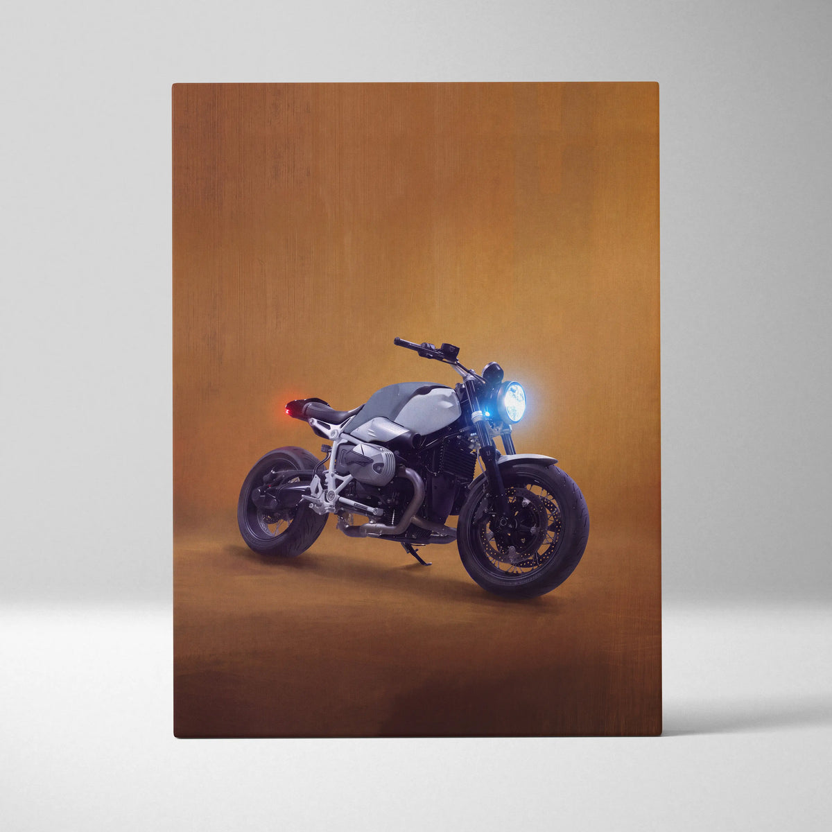 A sleek silver and black bmw r1200gs motorcycle wall art with glowing headlight in an artistic studio setting