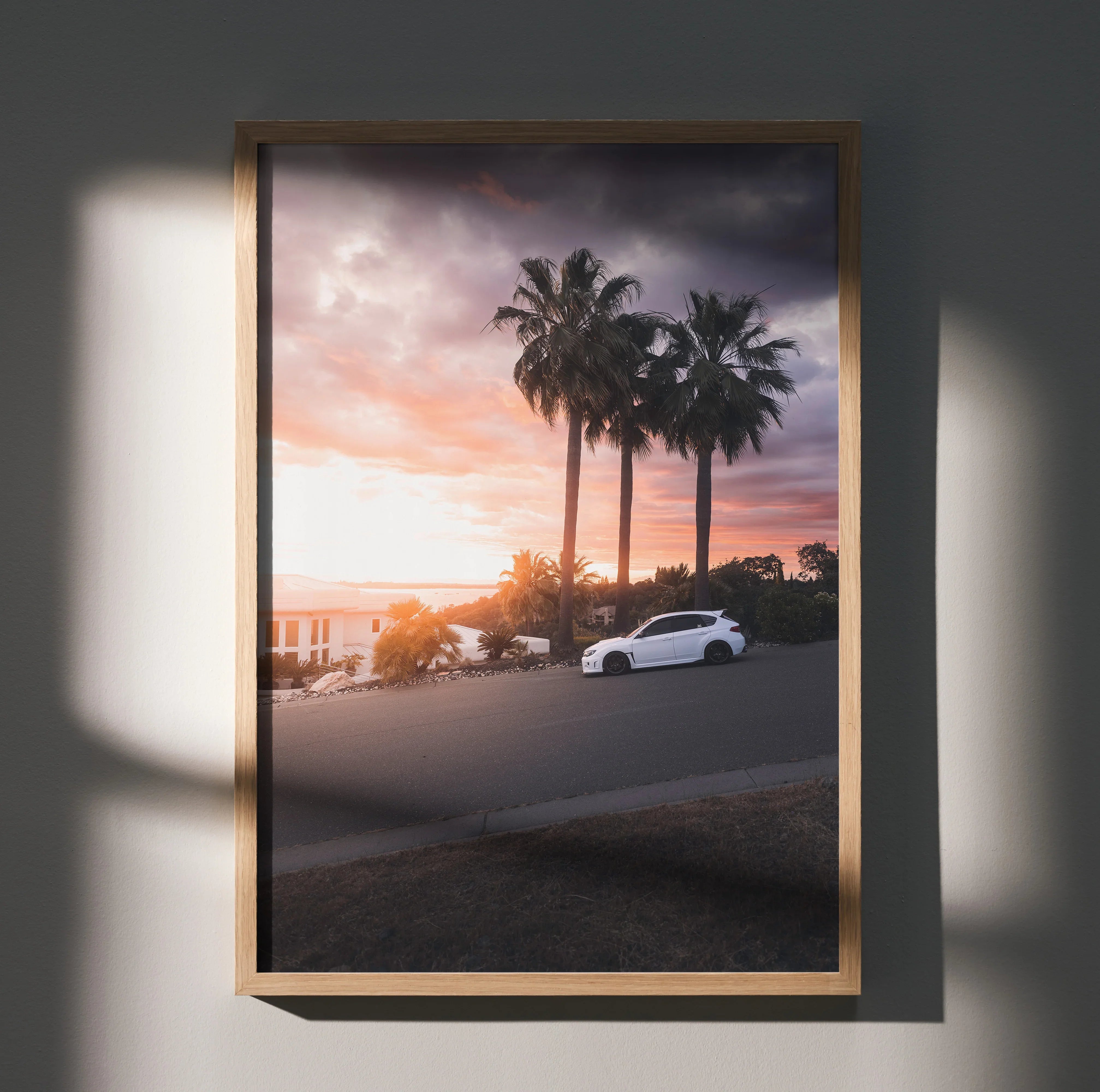 Subaru WRX STI driving on coastal road at sunset with palm trees poster wall art.