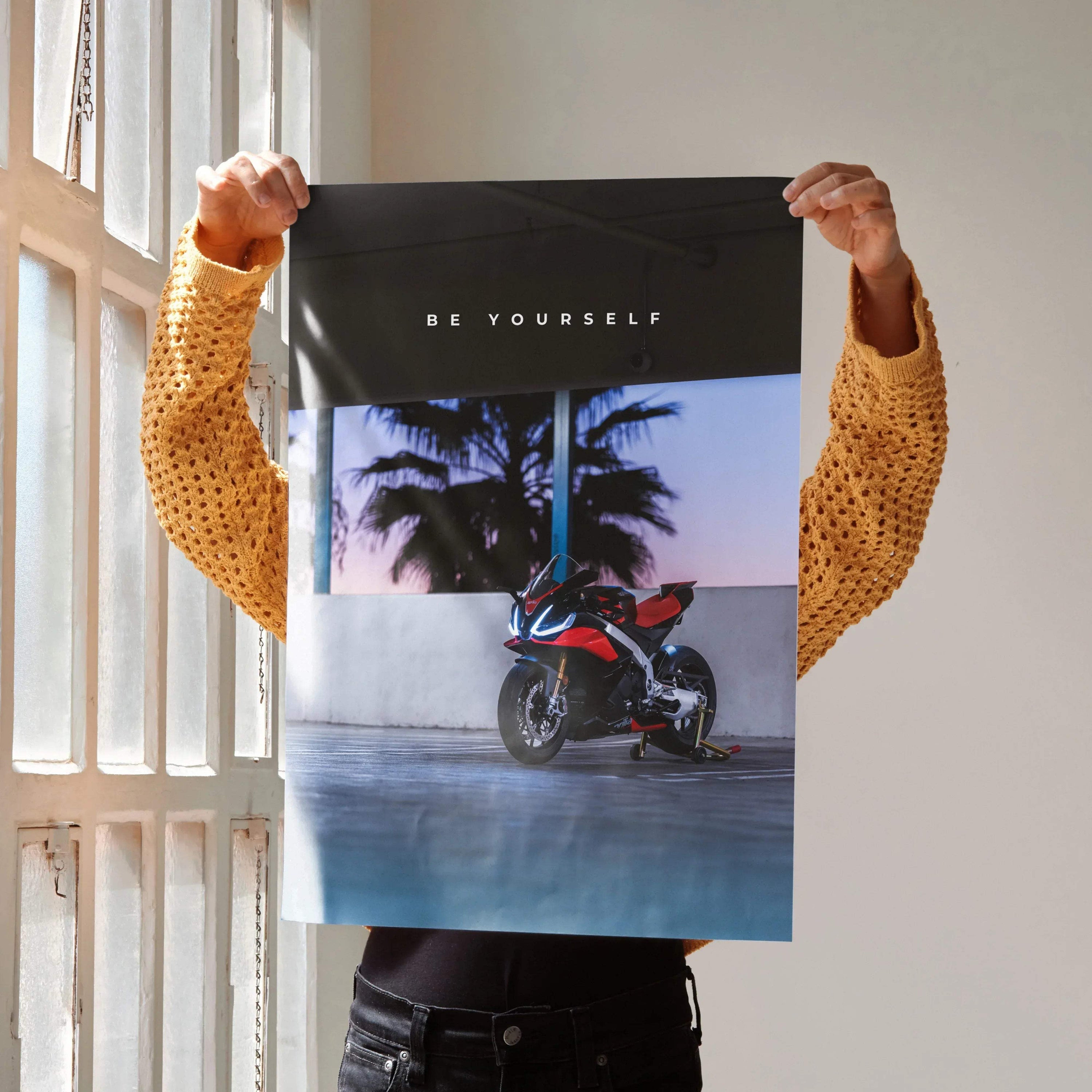 Motivational poster wall art featuring Aprilia RSV4 1100 Factory motorcycle with palm trees and "Be Yourself" text.