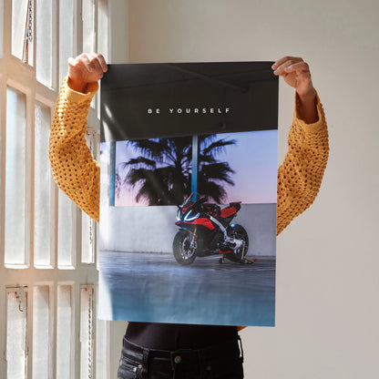 Motivational poster wall art featuring Aprilia RSV4 1100 Factory motorcycle with palm trees and "Be Yourself" text.