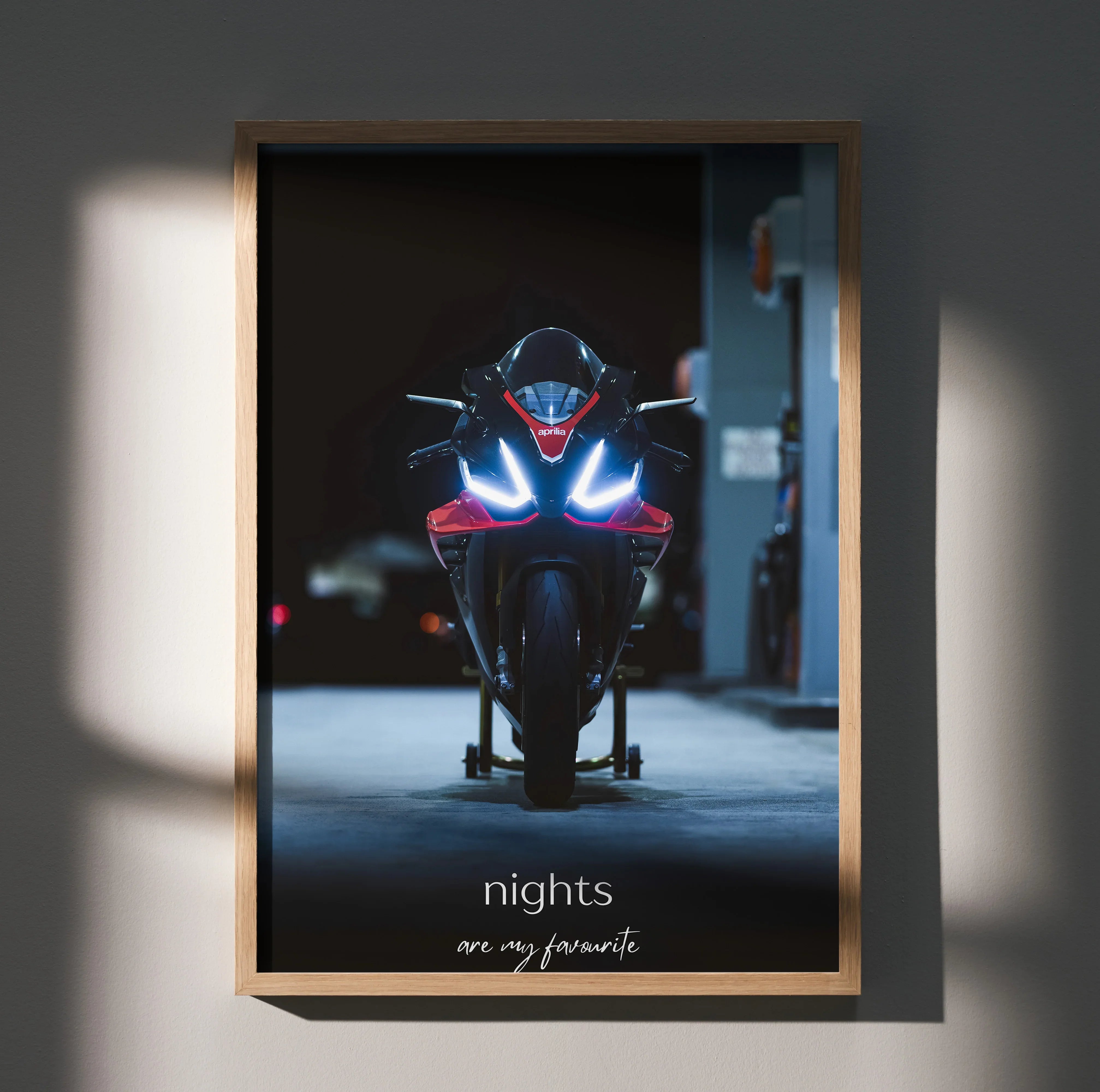 Motivational poster wall art featuring front view of Aprilia RSV4 1100 Factory motorcycle with bright headlights at night.