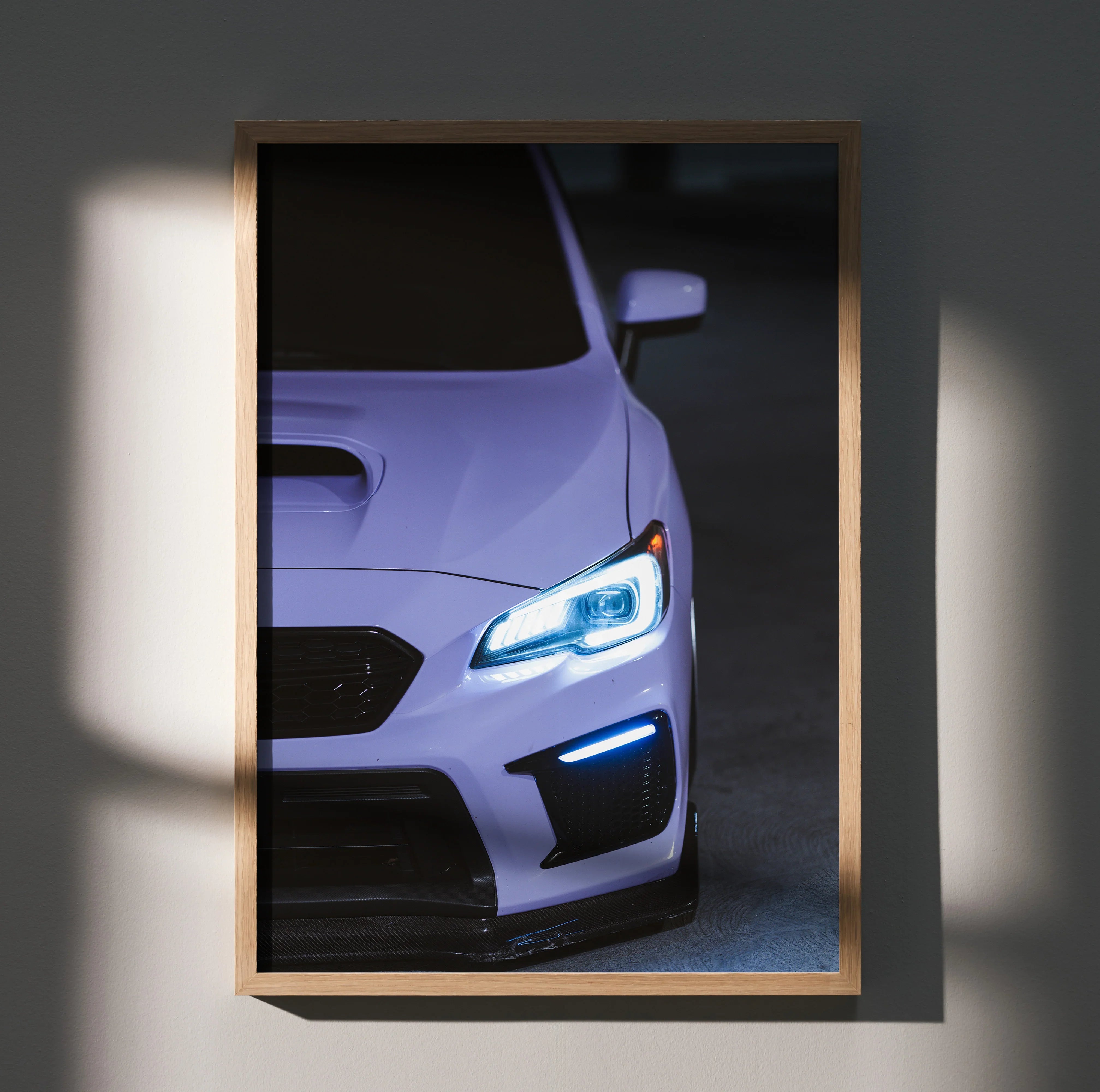 Subaru WRX close-up with glowing headlights and aggressive front grille wall art poster in wooden frame.