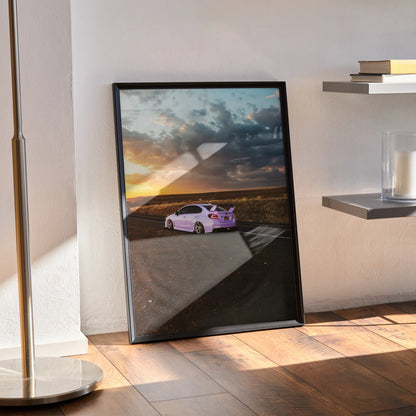 Subaru WRX at sunset on scenic road poster wall art in black frame on wooden floor.