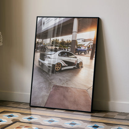 Mitsubishi Evo 10 poster wall art showing silver sports car with gold wheels in a modern garage setting.