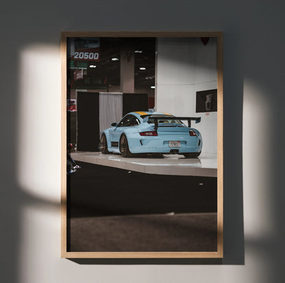 Porsche 911 Carrera 4 in light blue displayed on wall art poster with wooden frame.