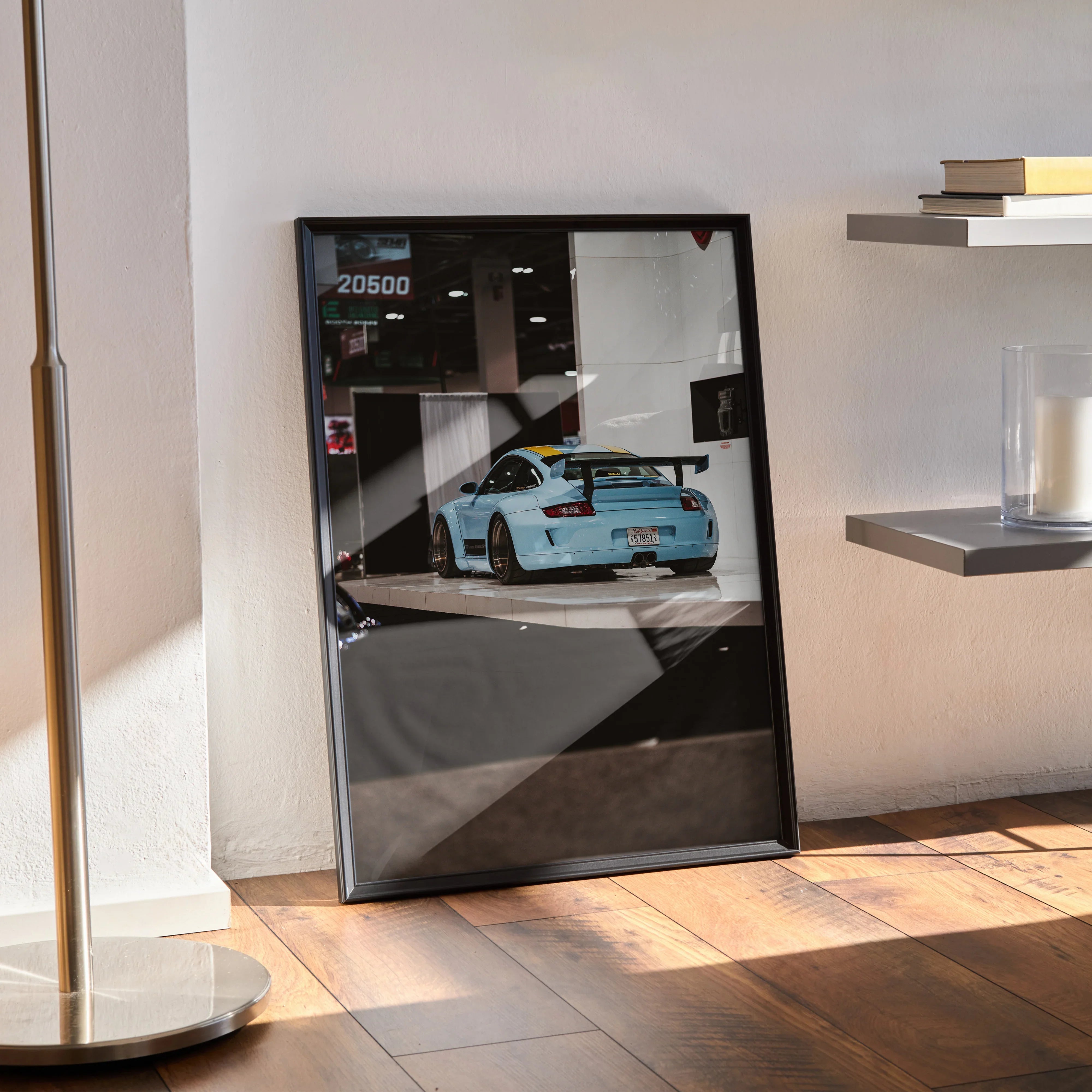 Porsche 911 Carrera 4 poster with blue car rear view in black frame leaning against wall wall art.