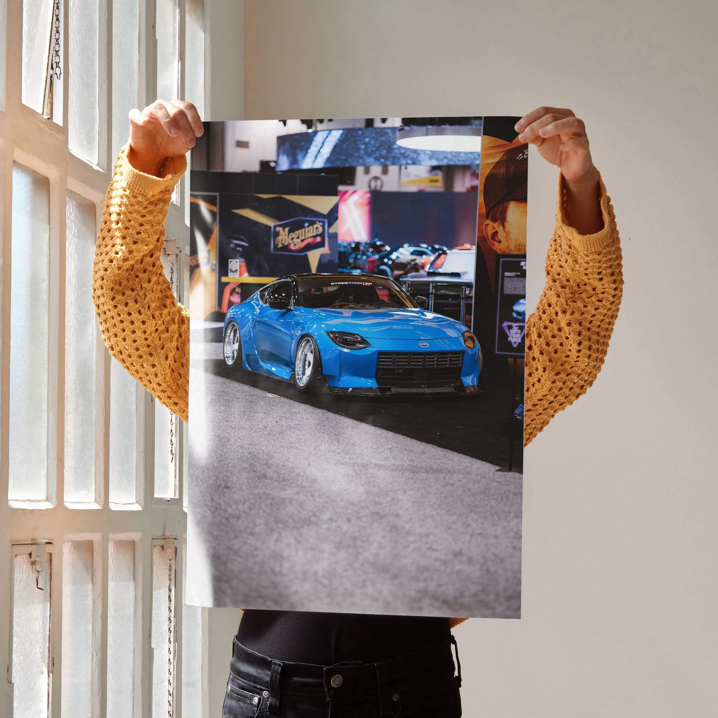 Nissan Z (RZ34) blue sports car poster held against window light, high-resolution wall art.