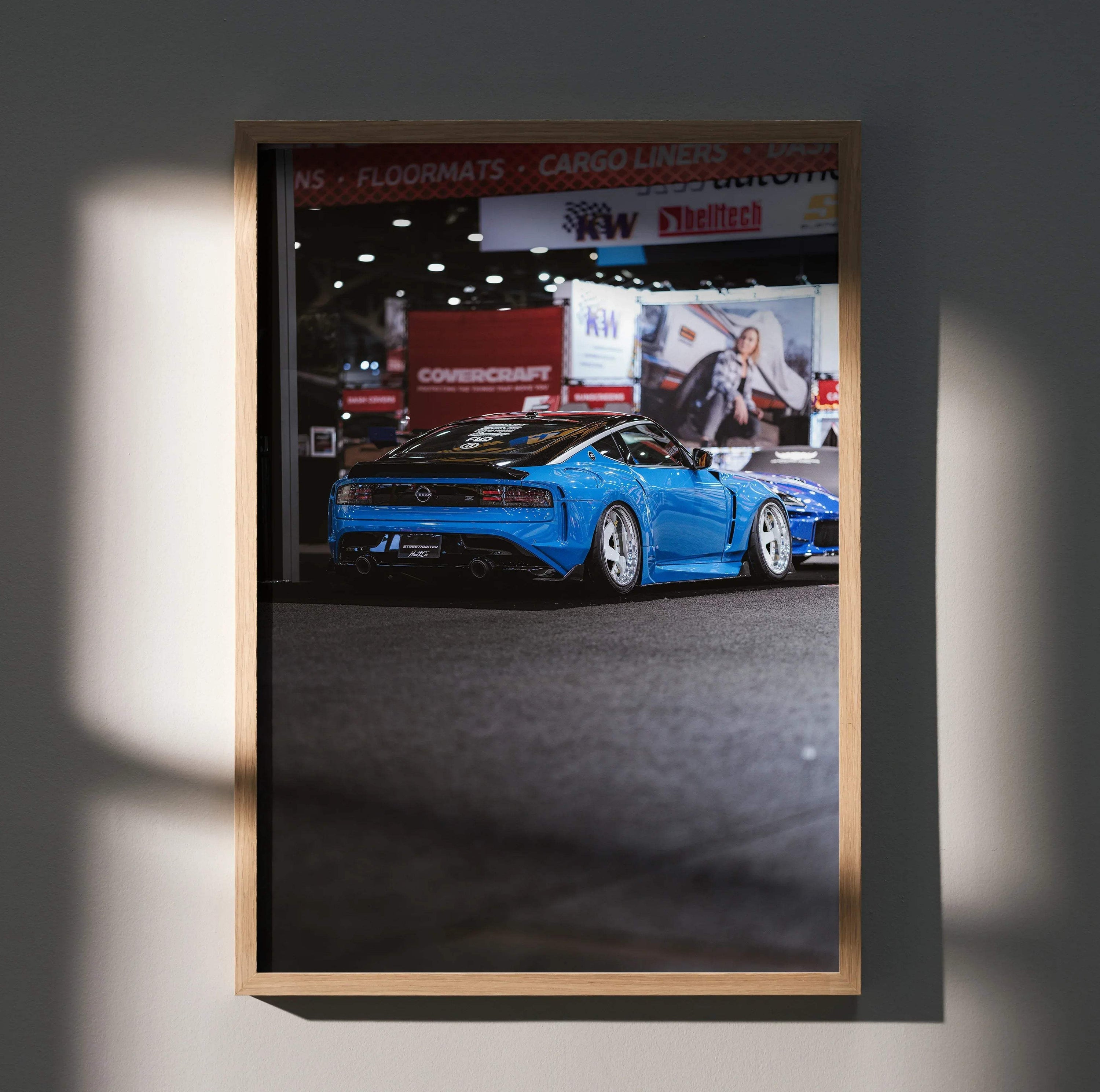 Nissan Z (RZ34) blue sports car poster wall art in wooden frame with showroom backdrop.