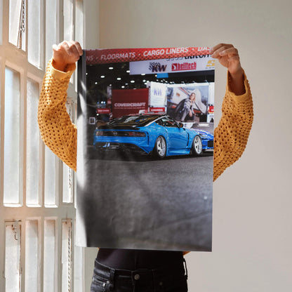 Nissan Z (RZ34) blue sports car poster held indoors, showcasing sleek automotive wall art design.
