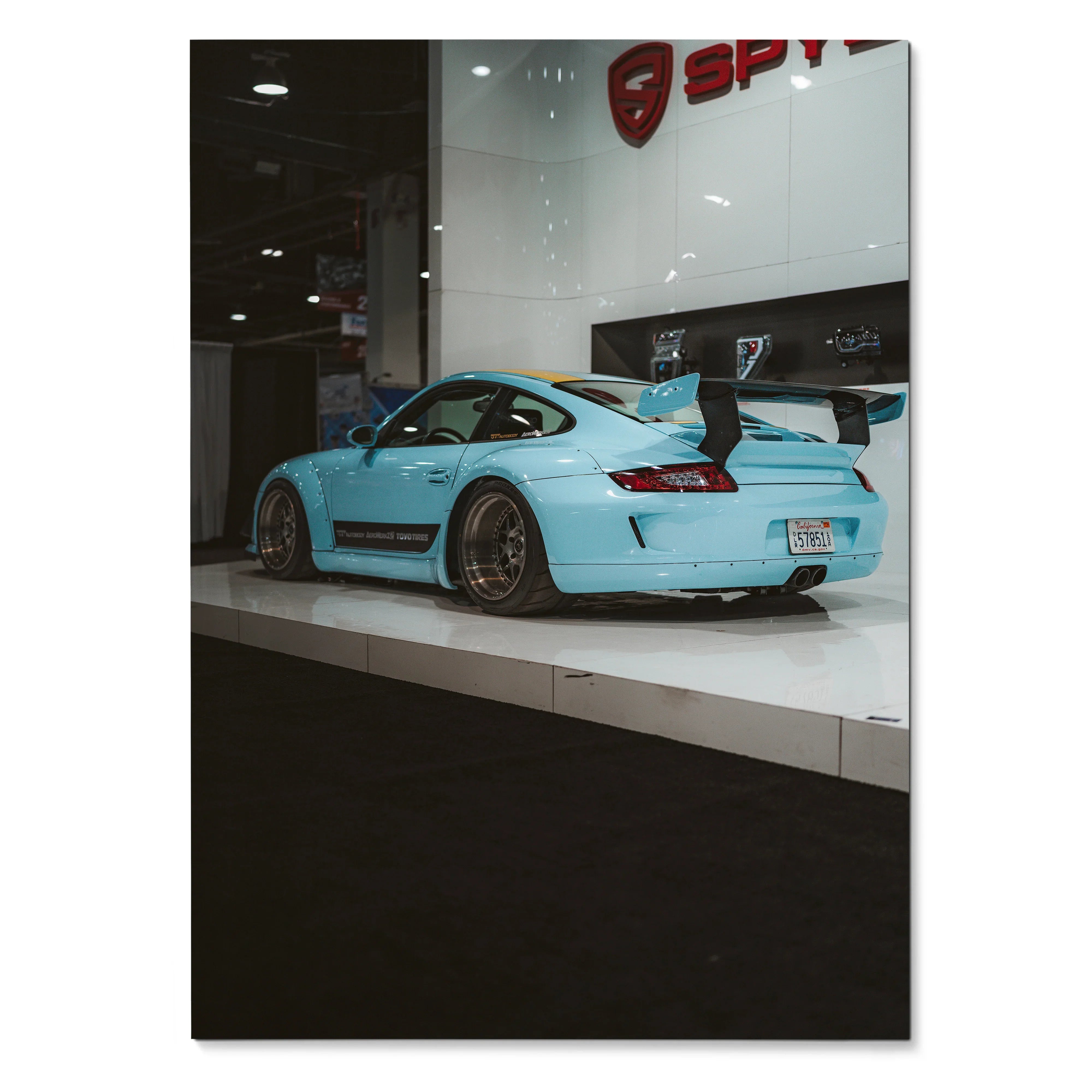 Porsche 911 Carrera 4 light blue sports car with rear wing on glossy showroom poster wall art.