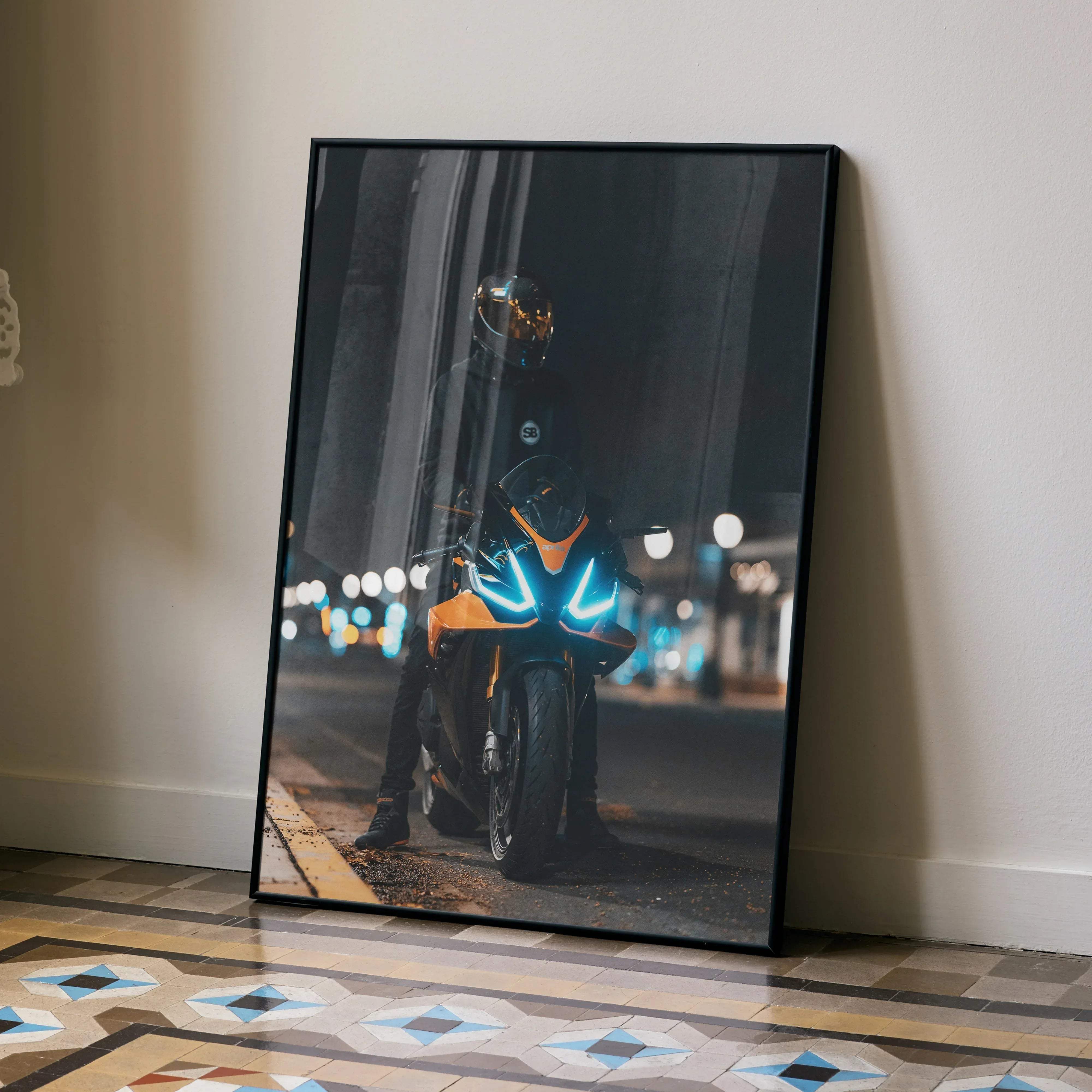 A framed biker poster featuring an Aprilia RSV4 motorcycle with glowing blue headlights and an orange fairing