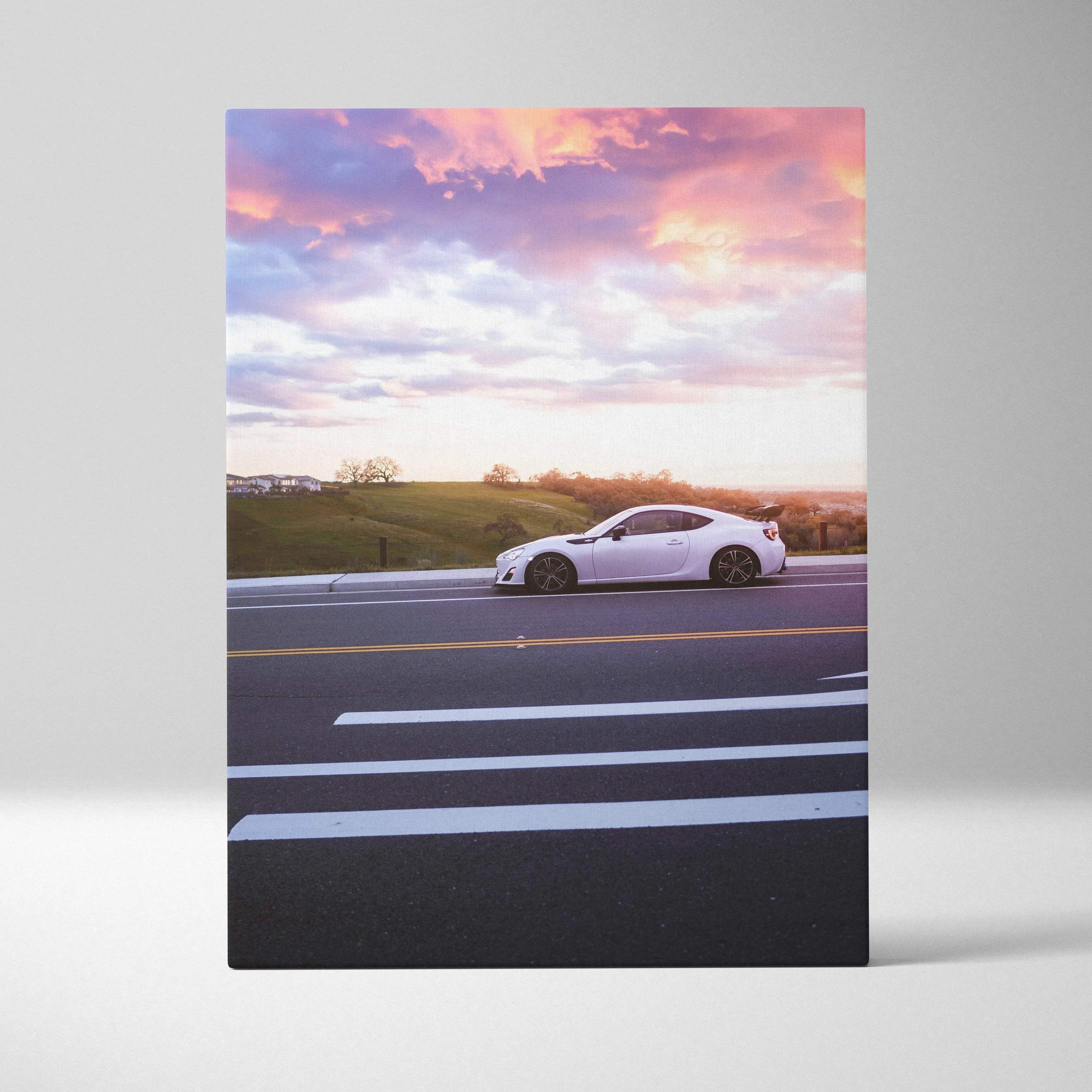 White Toyota FRS car on road at sunset with pink and orange sky canvas wall art.